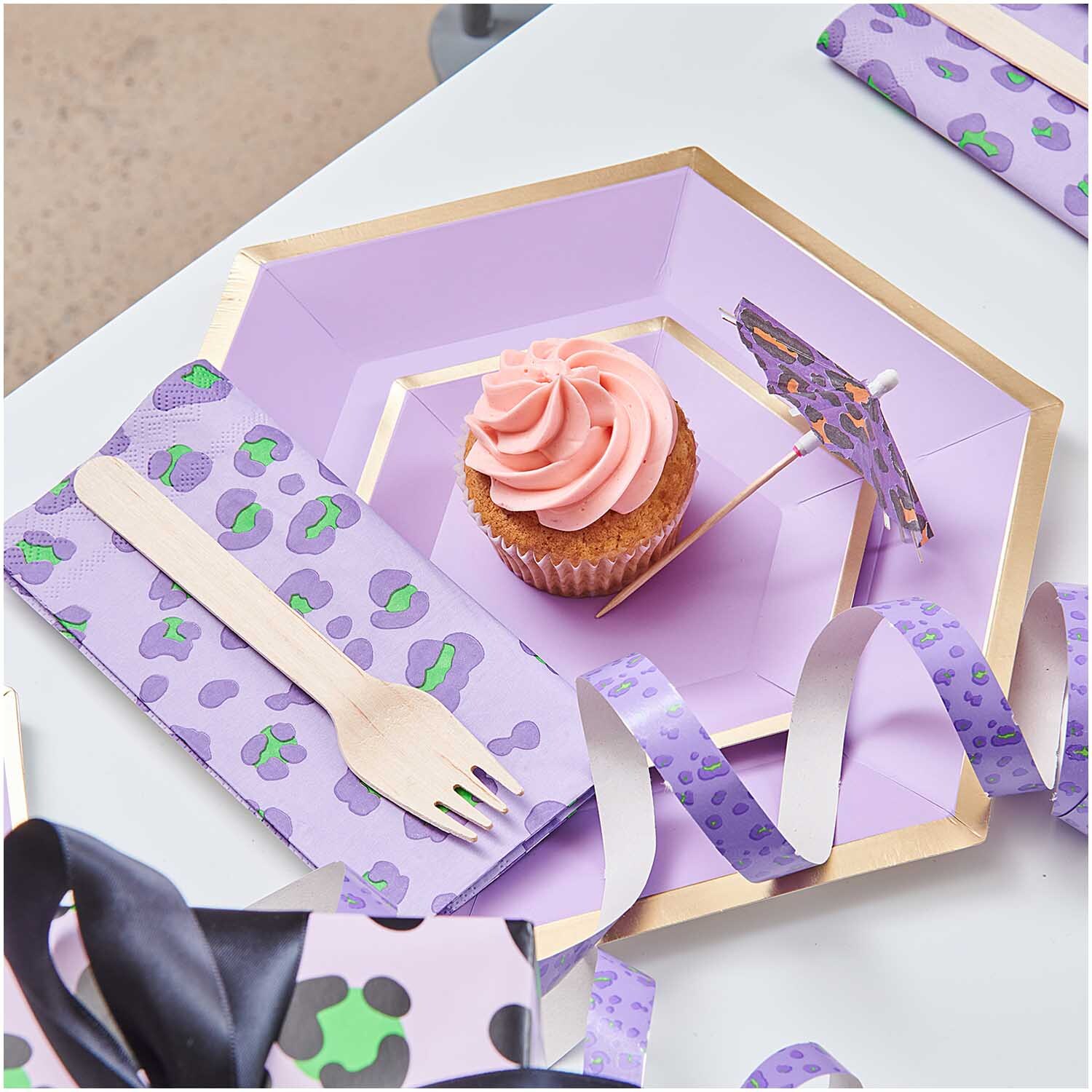 Servietten Acid Leo in flieder-grün von Rico Design, dekoriert mit einem Cupcake und Partyzubehör.