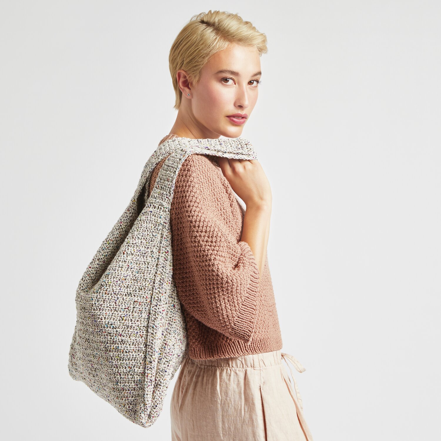 Made by Me No. 20: Frau mit gestrickter Tasche in neutralen Tönen, getragen über der Schulter.
