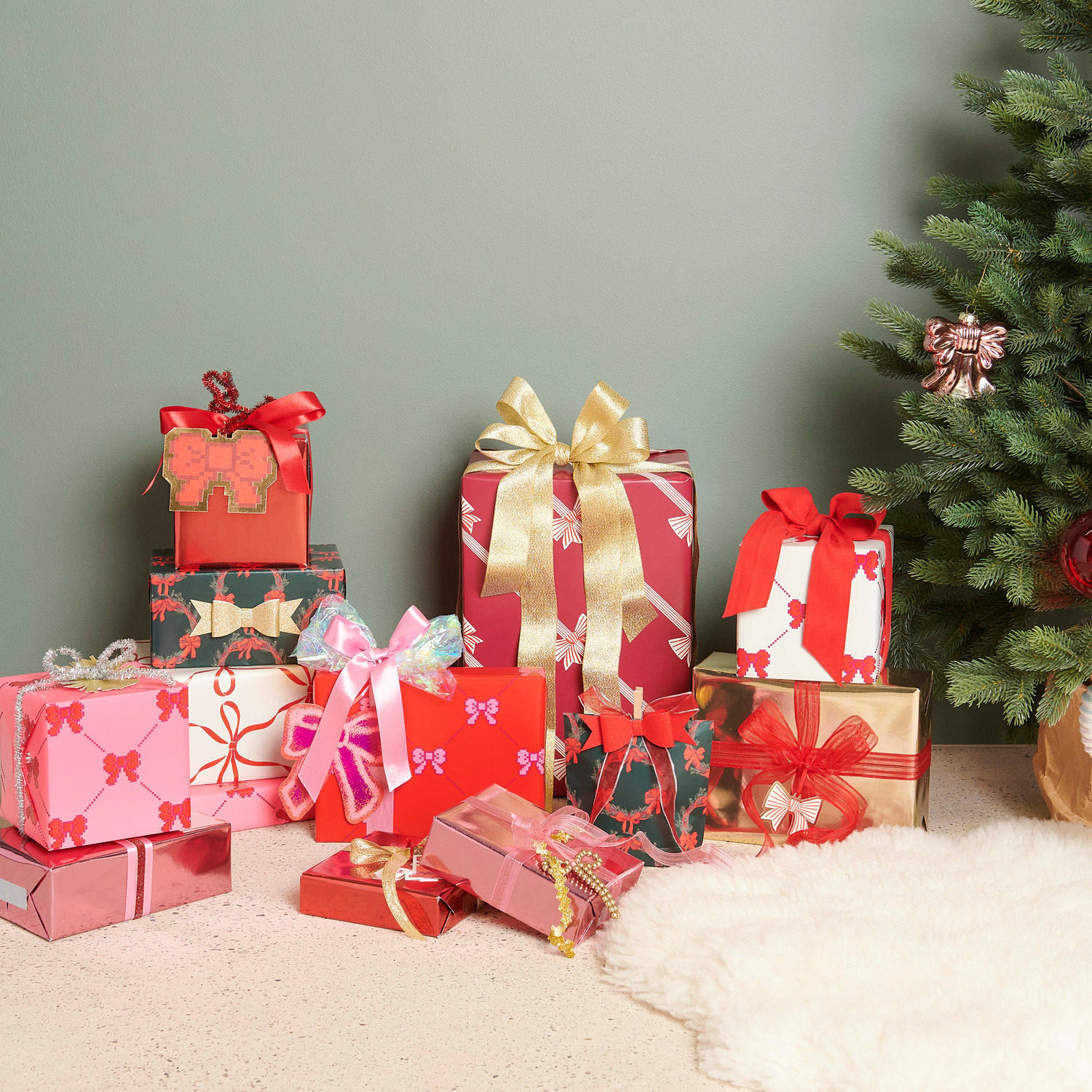Organzaband Grob Pink/Gold: Geschenke in Rot und Gold mit Schleifen, vor einem Weihnachtsbaum arrangiert.