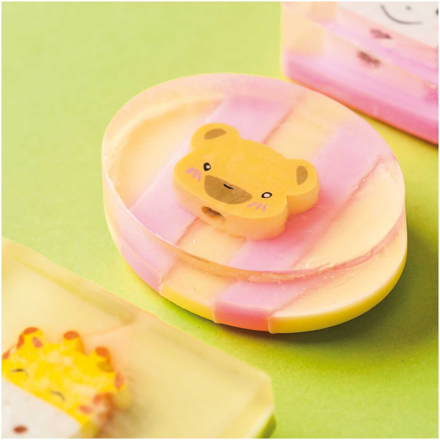 Gießseife transparent mit niedlichem Bärenmotiv, pastellfarben, auf grünem Hintergrund platziert.