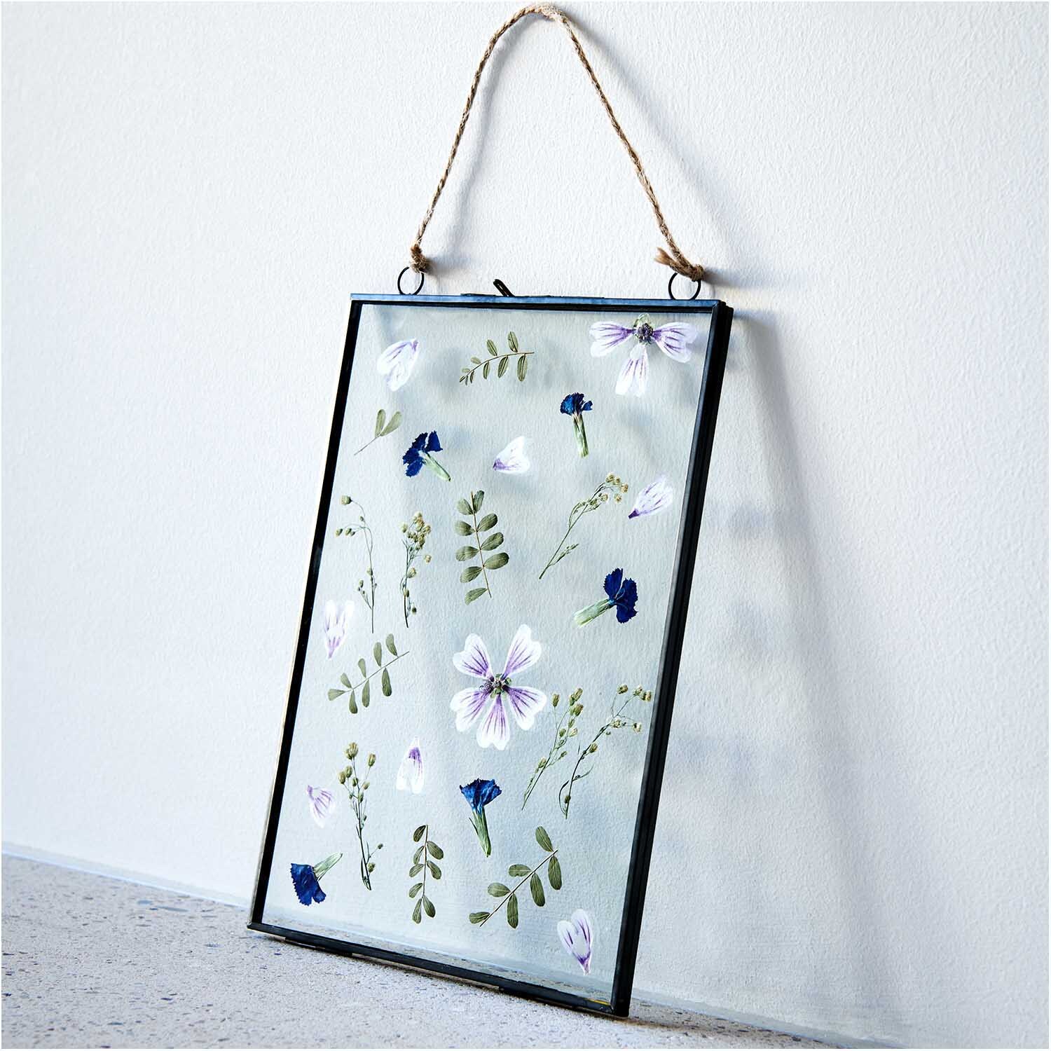 Metallrahmen zum Hängen mit doppelter Glasscheibe zeigt gepresste Blumen und Blätter. Ideal für stilvolle Wanddekoration.