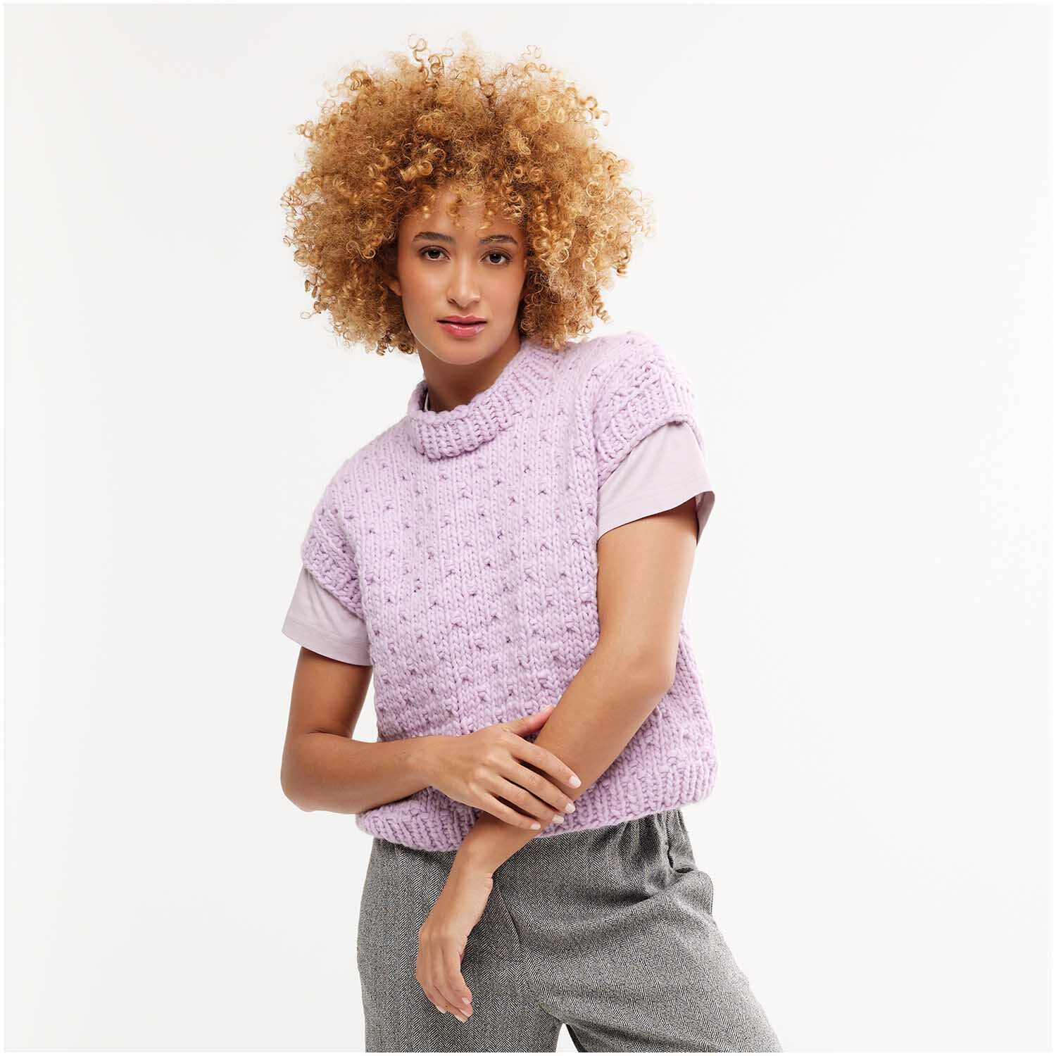 Strickset Pullunder Modell 02: Frau trägt lila Pullunder über grauem Shirt, kombiniert mit grauer Hose.