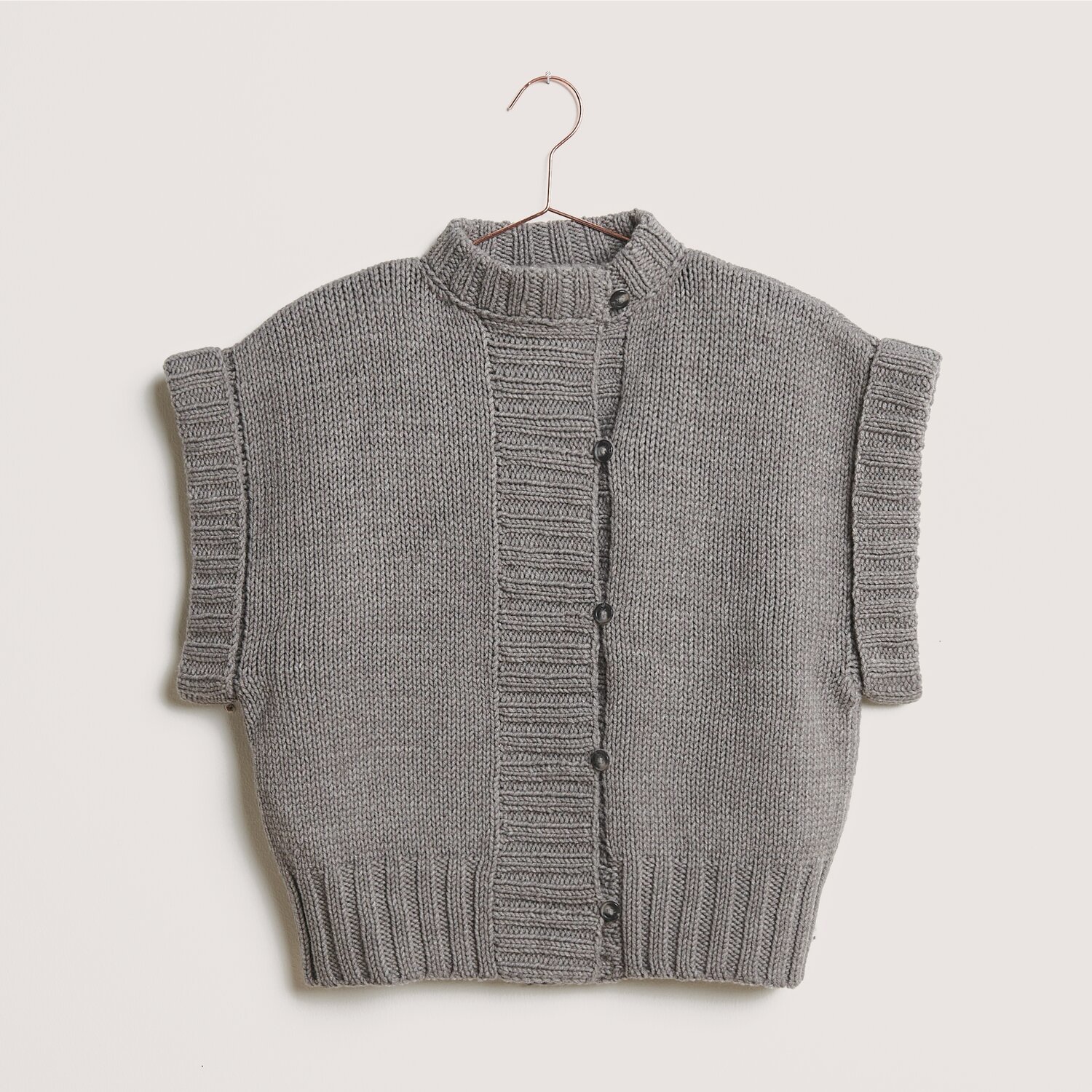 Classik, gestrickte Weste in Grau-Melange, aus Wolle Rödel, mit Knopfleiste und kurzen Ärmeln.