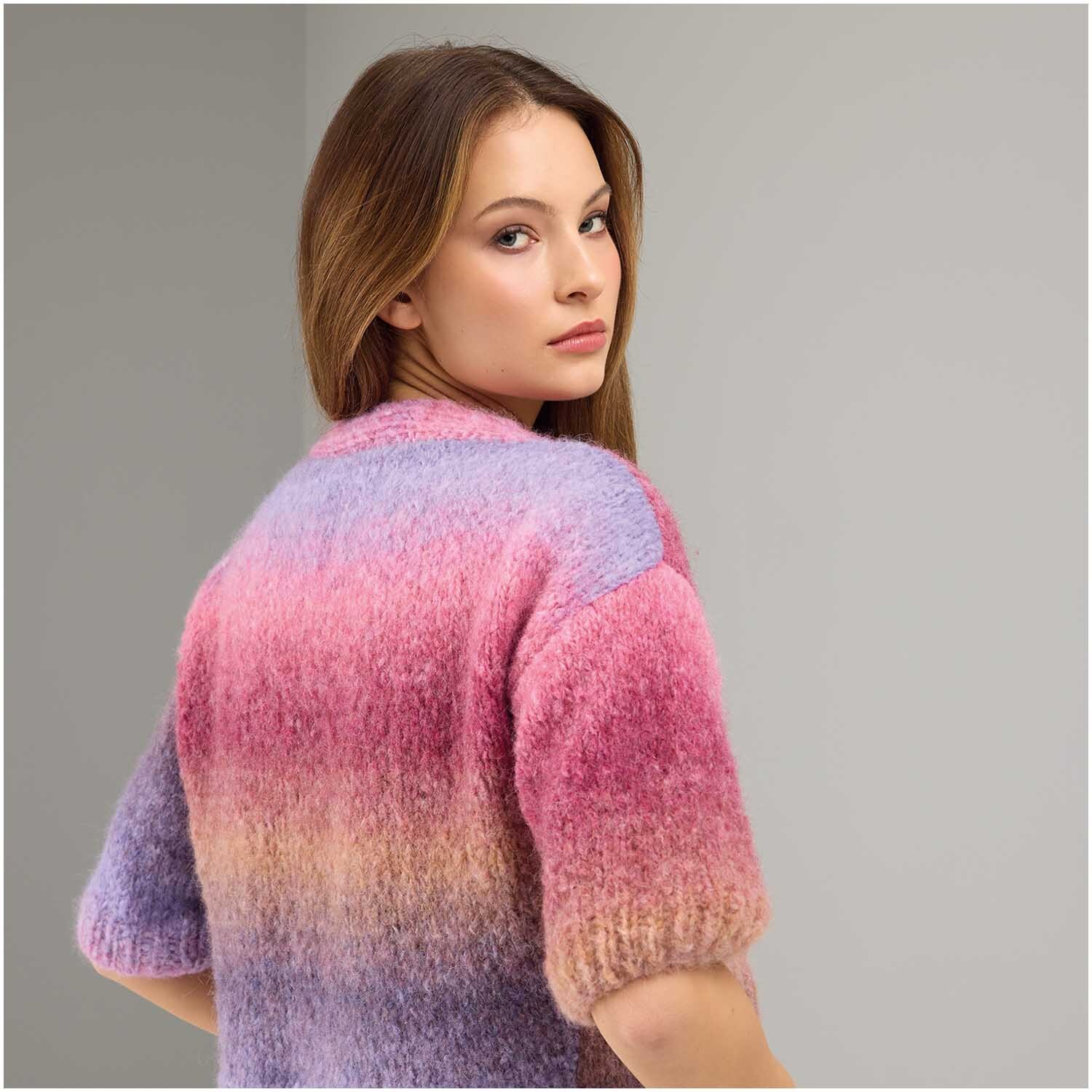 Strickset Kimonojacke Modell 01: Frau trägt bunte, gestrickte Jacke in Rosa- und Lilatönen.