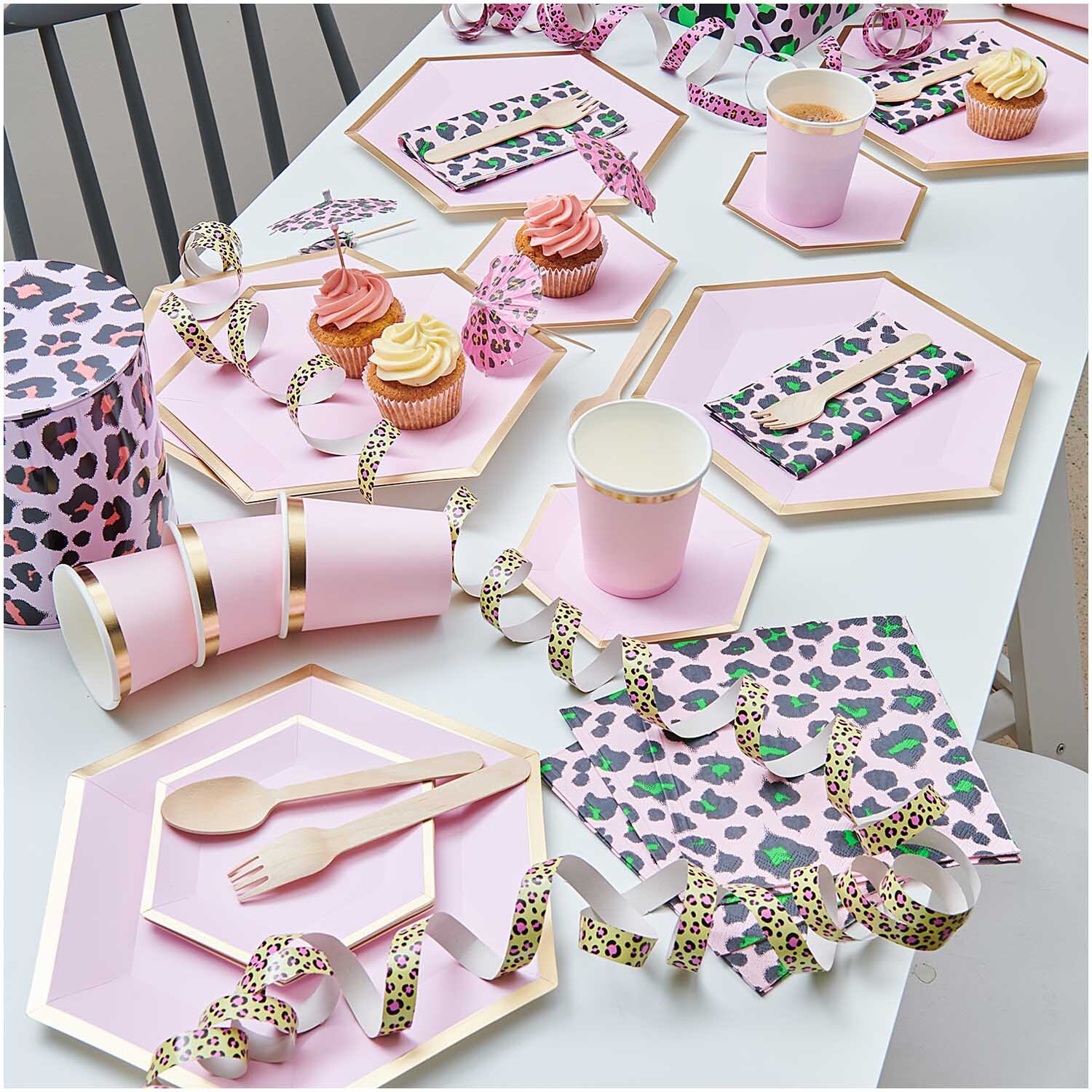 Pappteller Sechseck rosa-gold von Rico Design auf einem Tisch mit Partydekoration und Cupcakes.