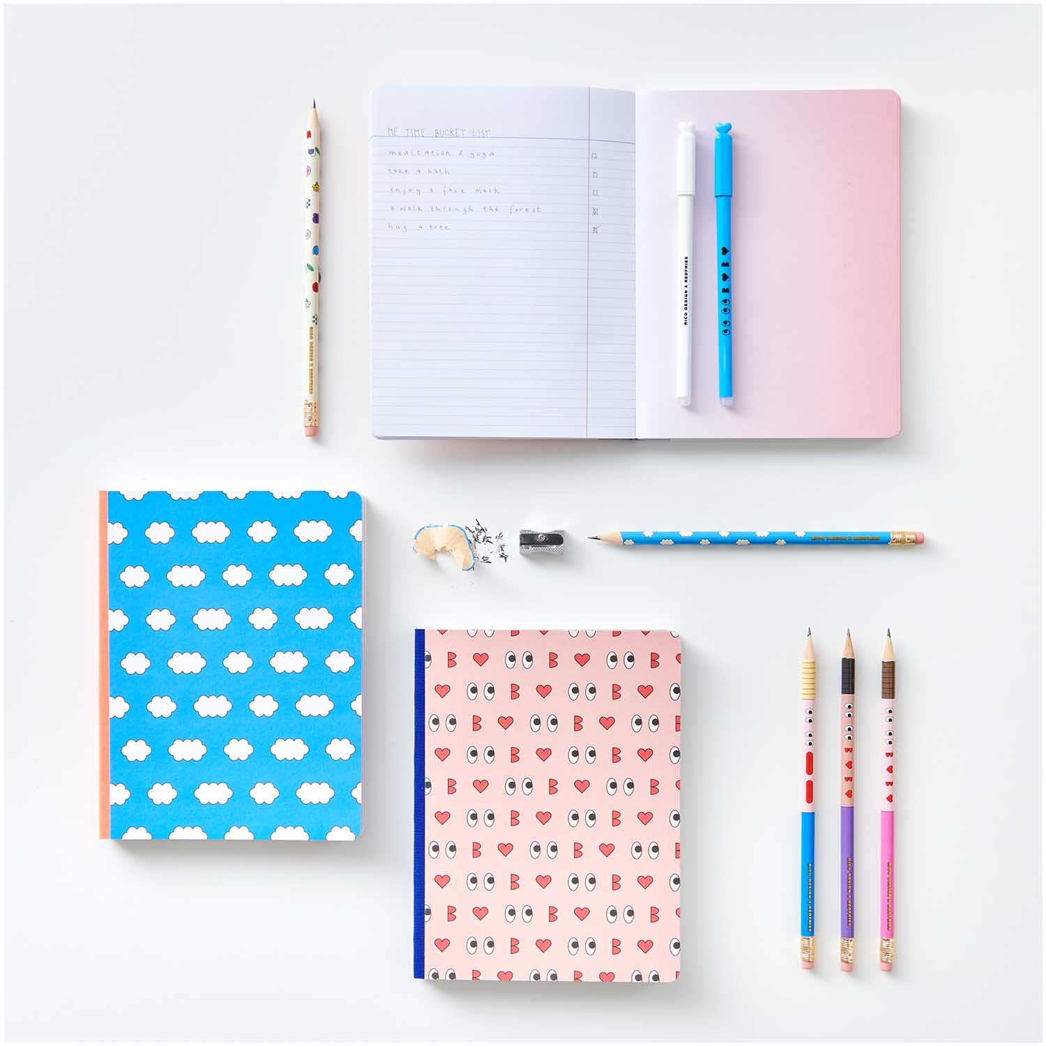 Rico Design x Redfries Notizbuch Liebe, umgeben von bunten Stiften und Notizbüchern auf weißem Hintergrund.