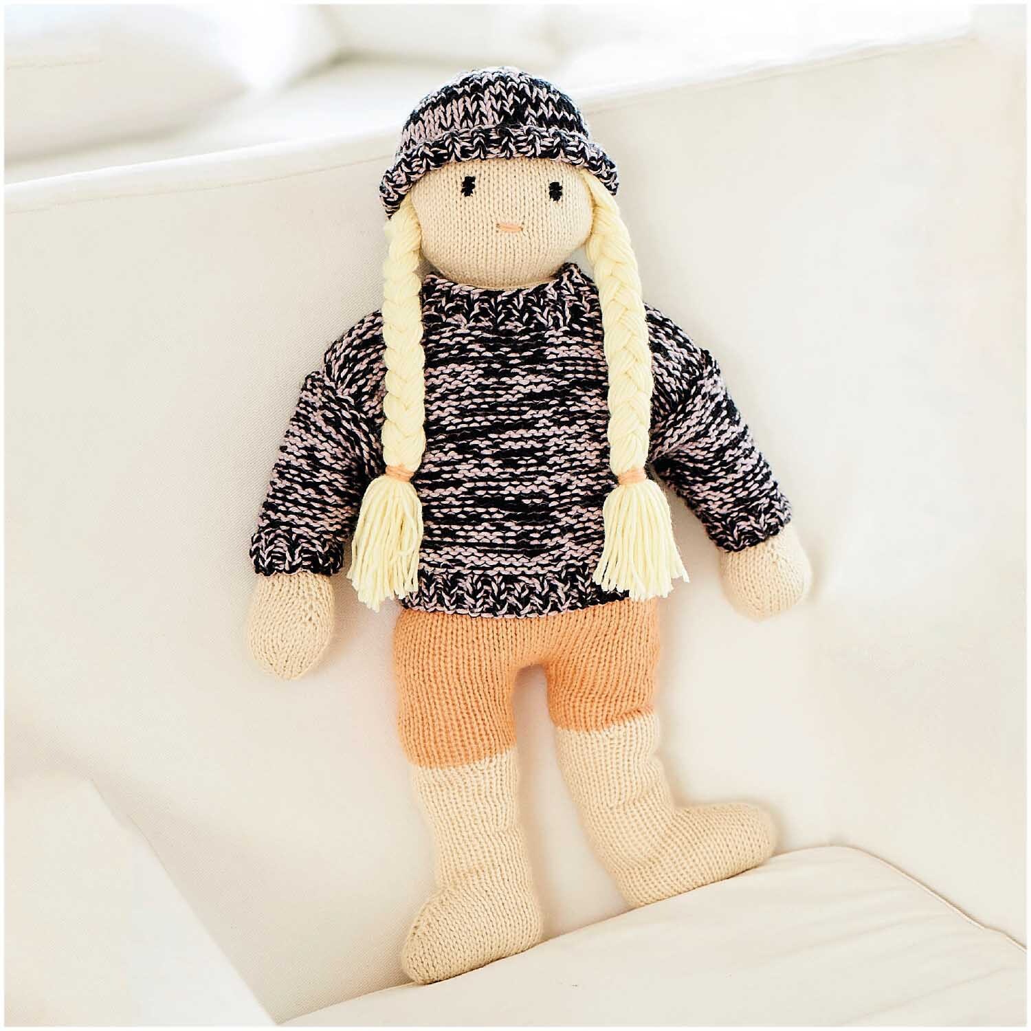 Rico Baby Dream dk uni - A Luxury Touch: Handgestrickte Puppe mit Zöpfen, trägt Mütze und Pullover.