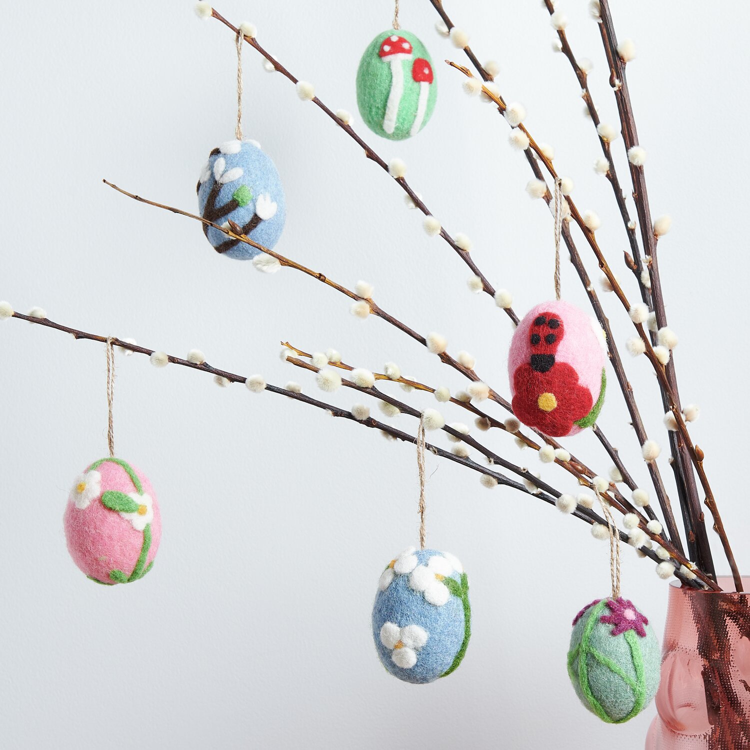 Aufhänger Filz-Ei Marienkäfer: Bunte Filz-Eier mit Naturmotiven an Zweigen in einer Vase, dekorativ arrangiert.