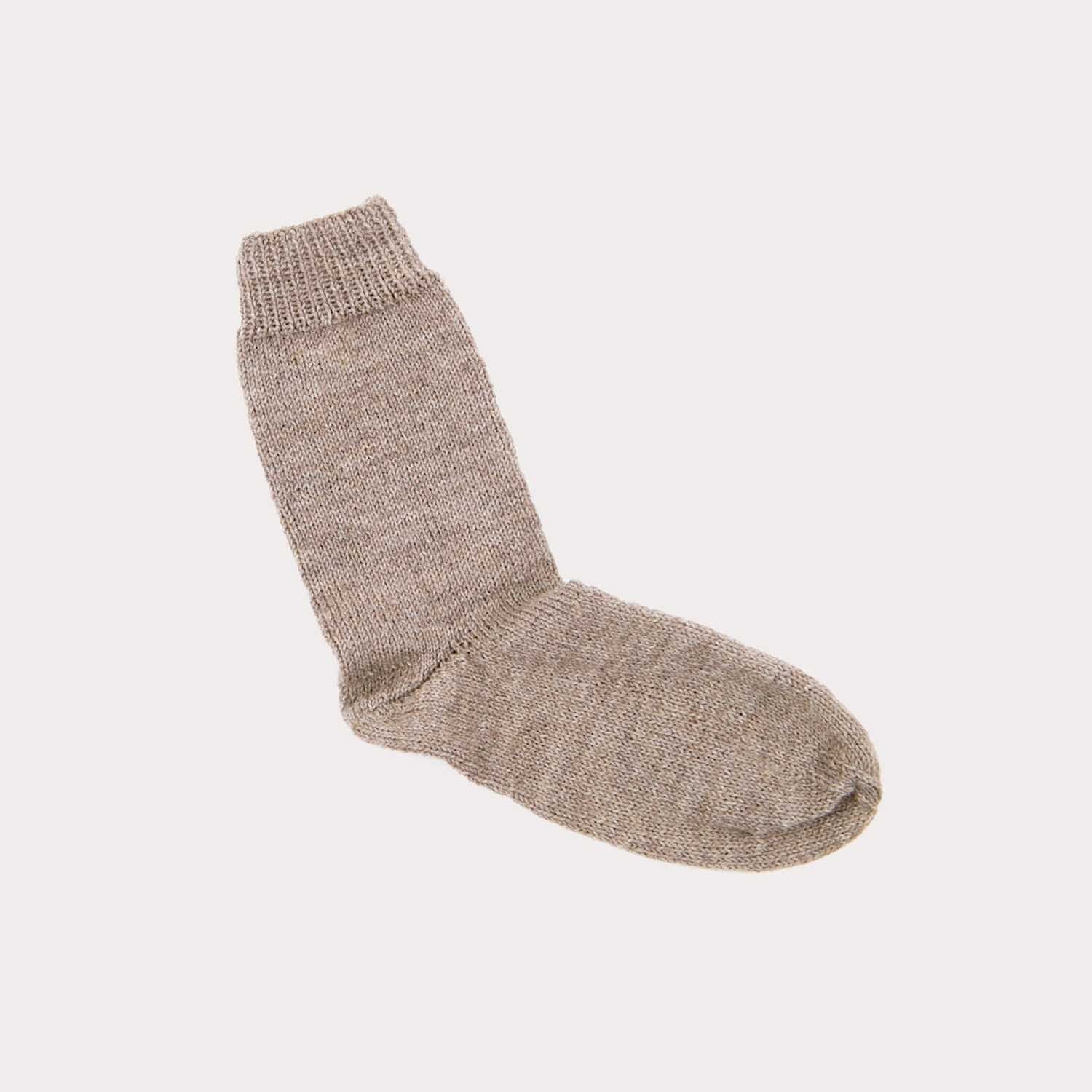 Strickanleitung Grundlage Socken: Ein einzelner, gestrickter, beiger Socke auf grauem Hintergrund.