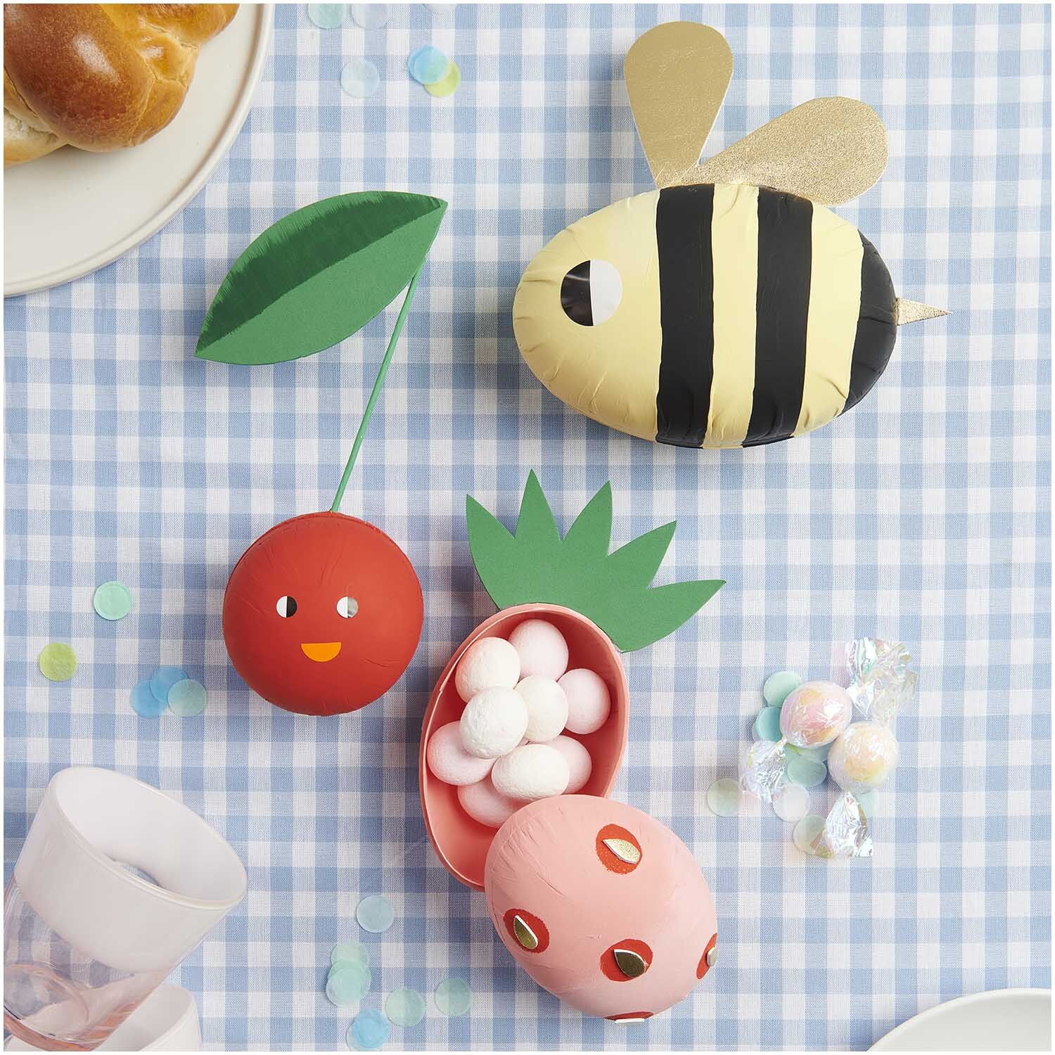 Pappmaché Eier natur 9cm, 12cm & 15cm 3 Stück auf kariertem Tischtuch mit bunten Dekorationen.