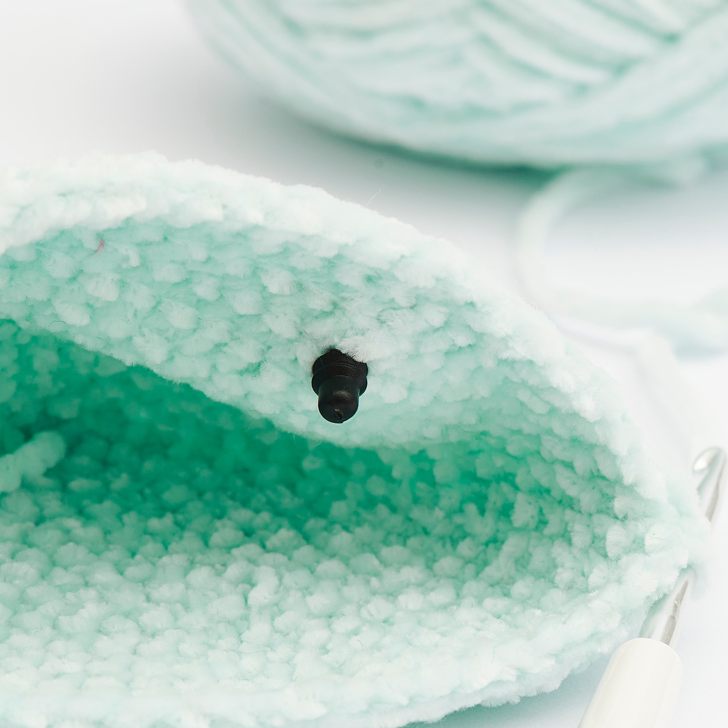 Sicherheitsaugen-Set für Kuscheltiere von Rico Design, gezeigt mit einem gestrickten Stoff in Pastellgrün.