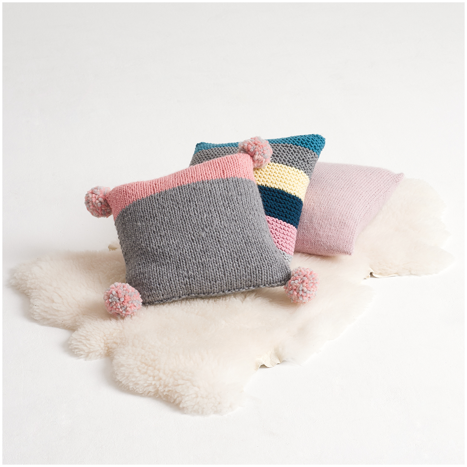 Polar Kissen aus Wolle Rödel Rico Design in verschiedenen Farben auf einem weißen Fell.