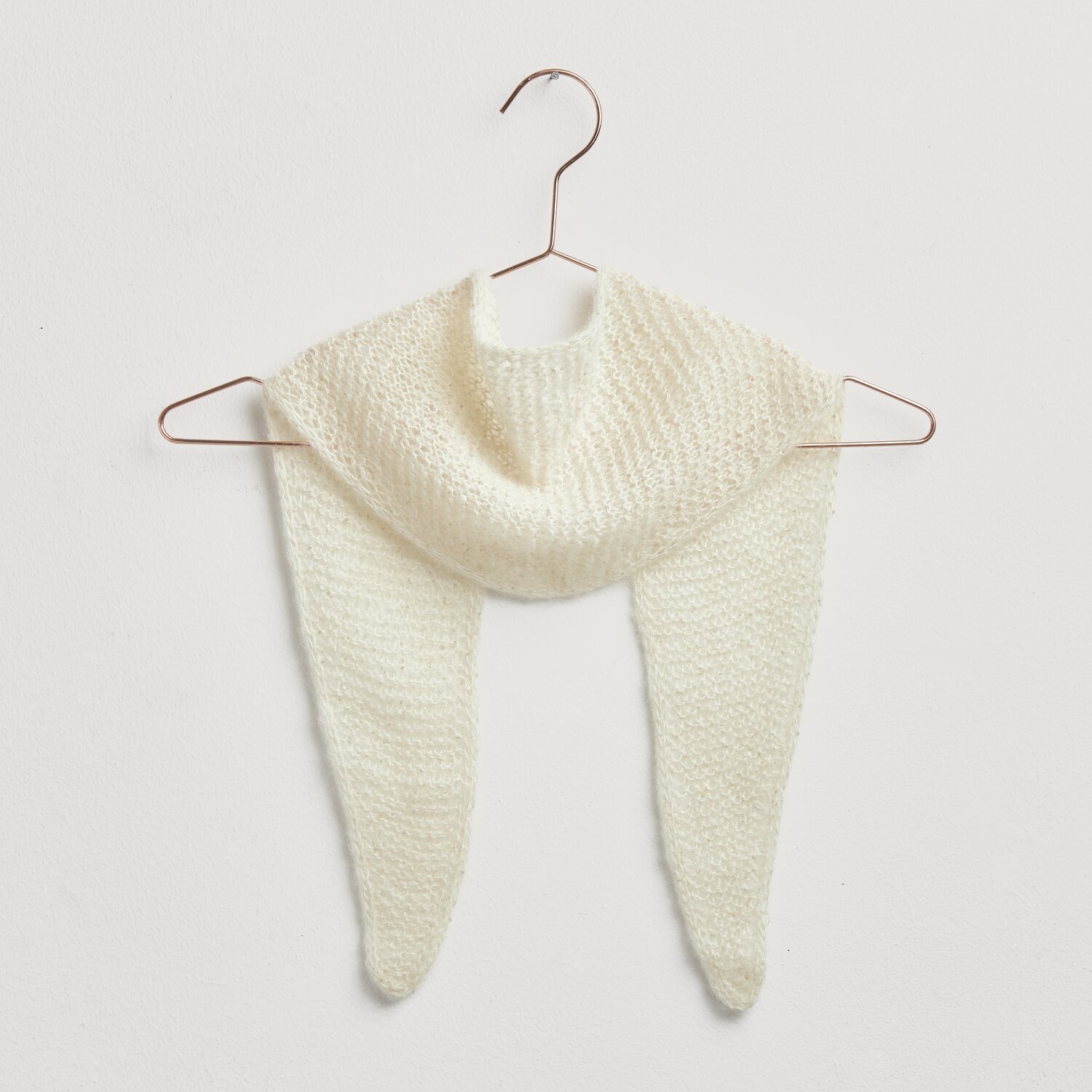 Strickset Mini-Dreieckstuch Modell 26 aus weichem Garn, cremefarben, auf einem Kleiderbügel präsentiert.