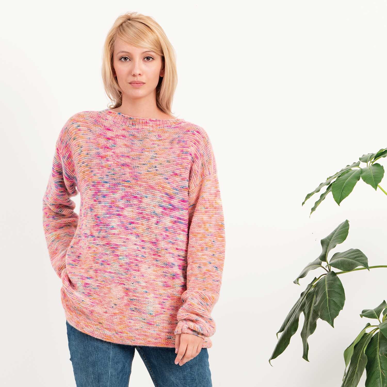 Luxury Hand-Dyed Happiness dk: Frau trägt gestrickten Pullover in Rosa-Blau von Rico Design, stehend neben Pflanze.