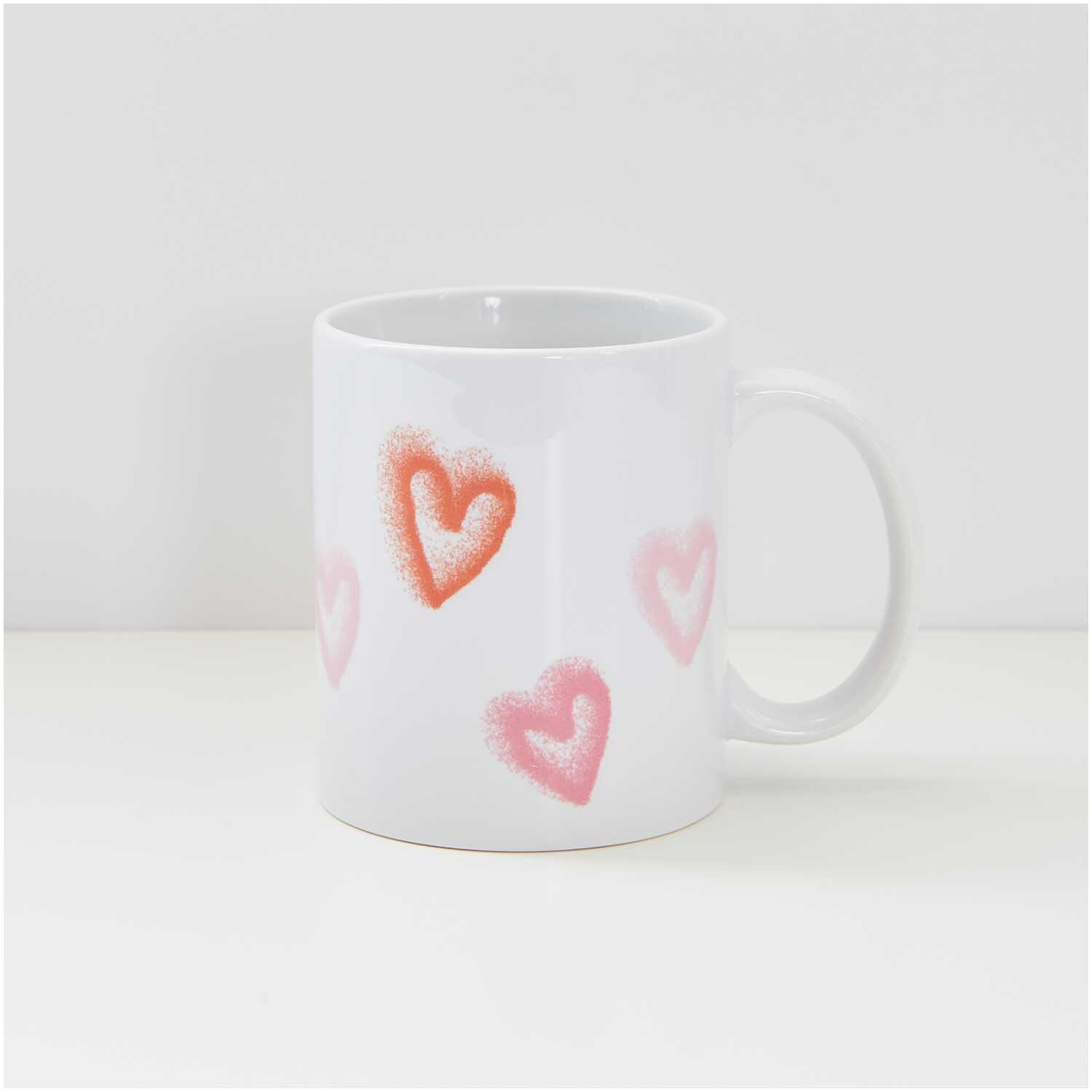 Transfermotiv Spray Herzen: Weiße Tasse mit roten und rosa Herzmotiven, ideal für kreative Designs. Marke: Rico Design.