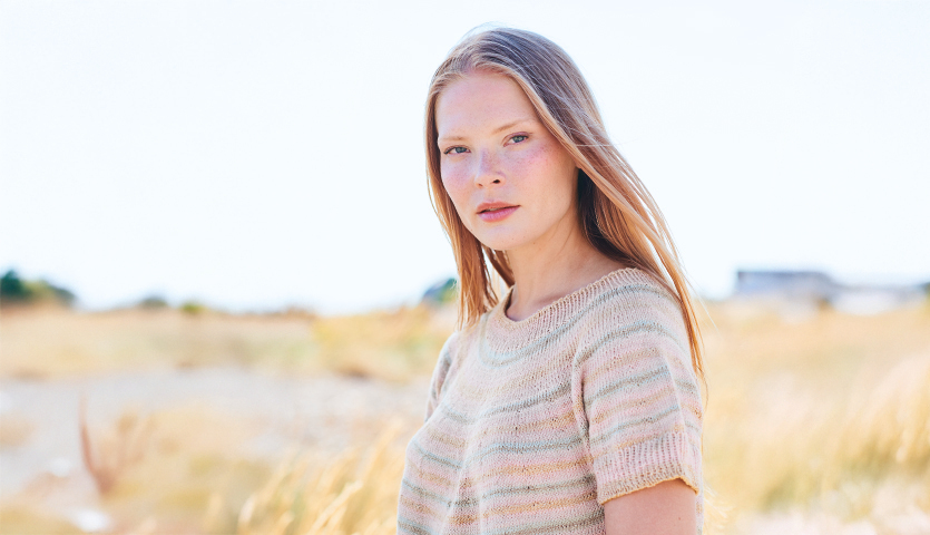 Strickanleitung Shirt aus Creative Cotton Camouflage: Frau in gestreiftem Strickshirt in natürlicher Landschaft.