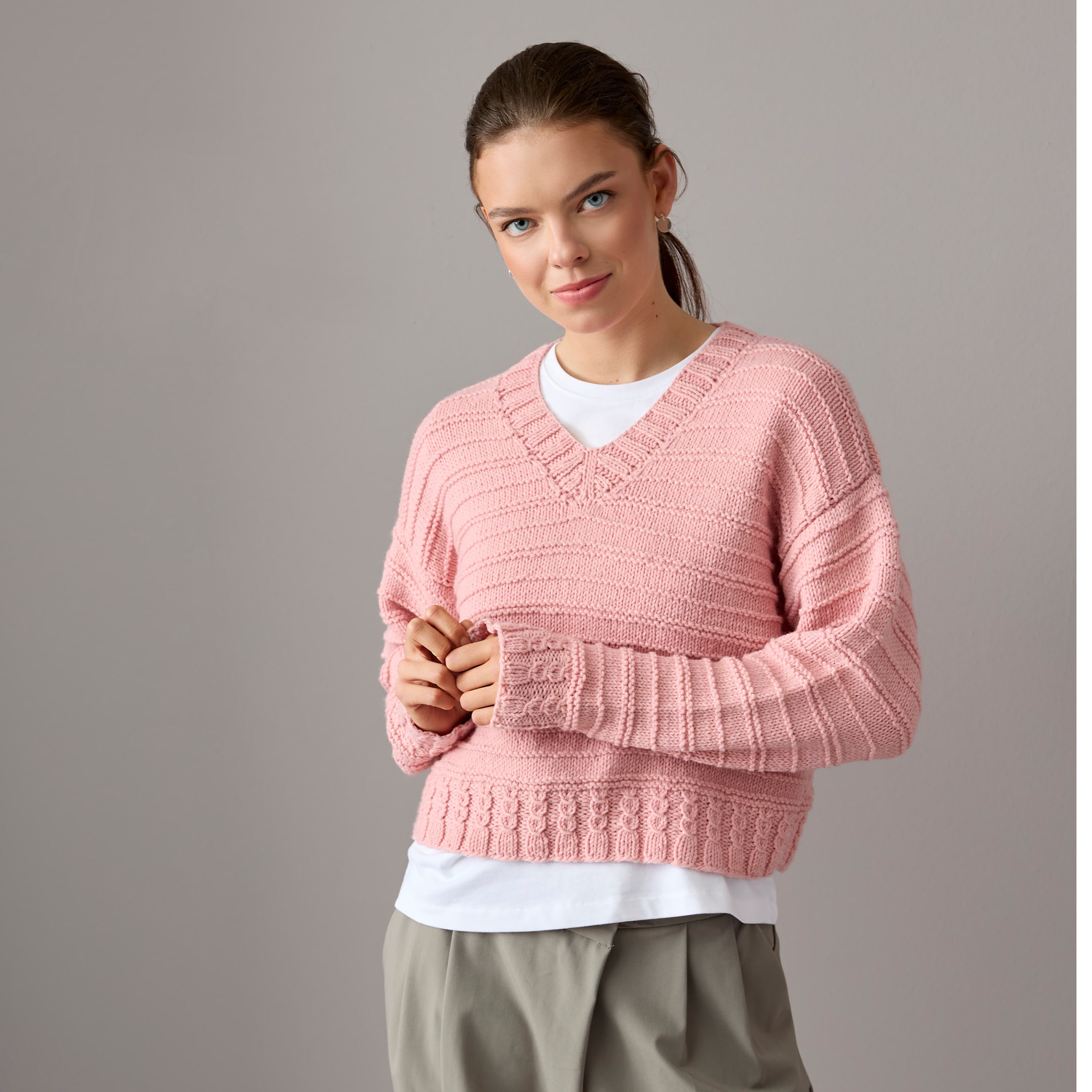 Vegan Cashmere Special: Frau trägt altrosa Strickpullover von Rico Design, lässig kombiniert mit weißem Shirt und grauer Hose.
