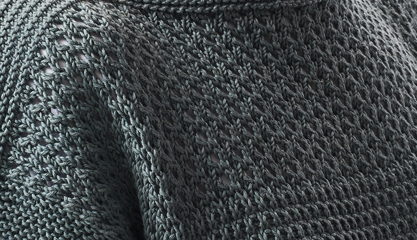 Strickanleitung Kurzarmpulli mit Lochmuster: Nahaufnahme eines grauen Pullovers mit feinem Lochmuster.
