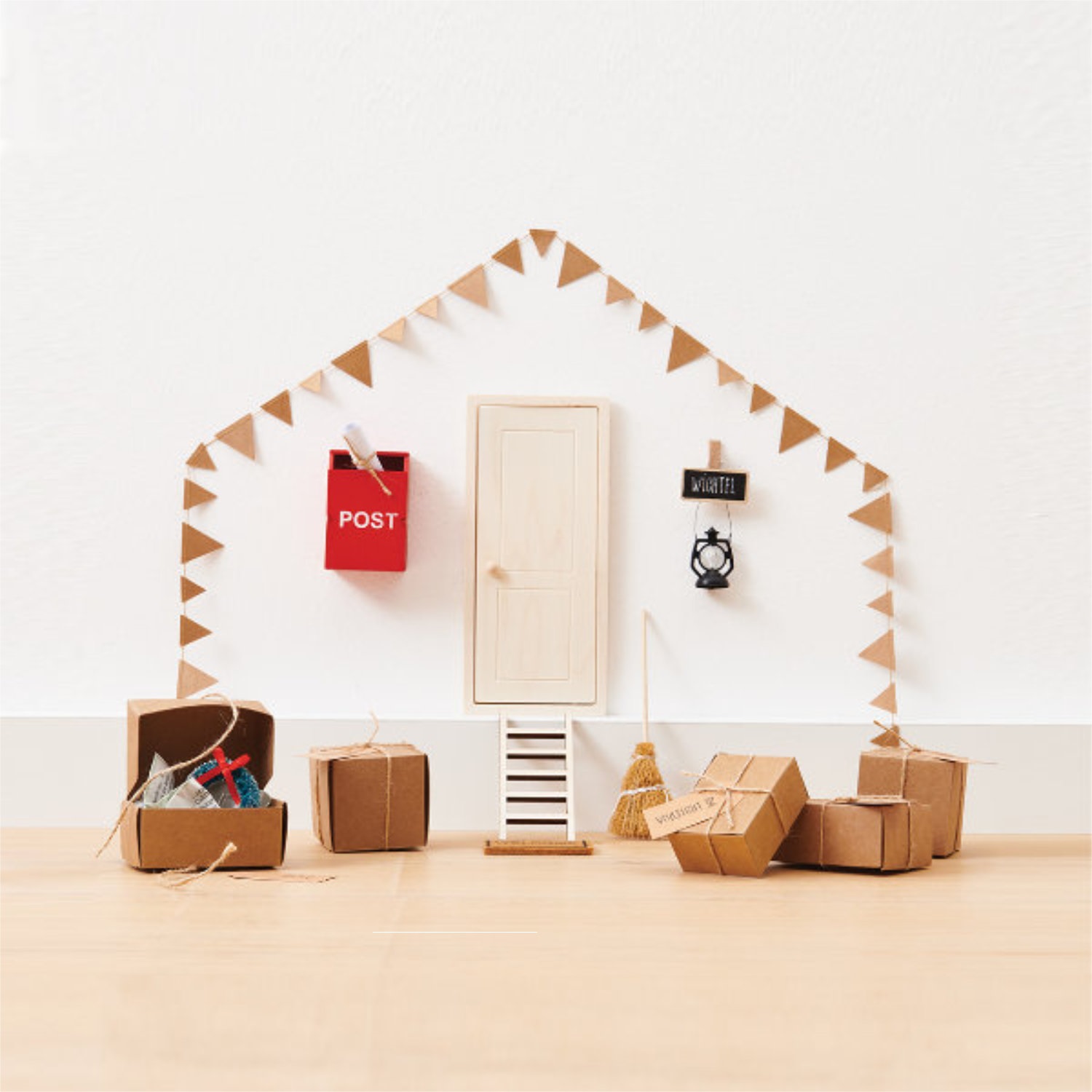 Wichtel-Haustür mit Treppe, Briefkasten und Mini-Girlande, sowie kleine Geschenke. Fotosetting weiße Wand.