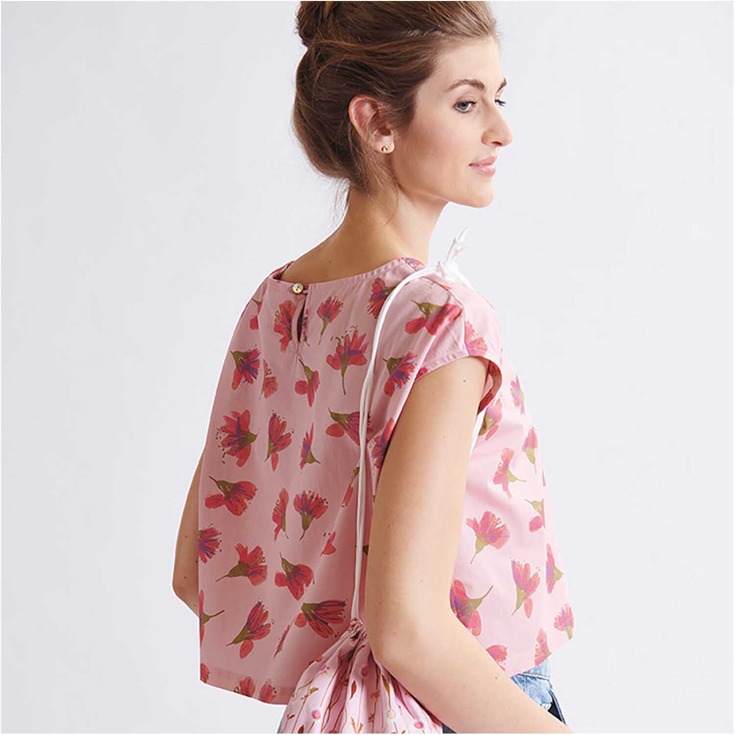 Meterware Druckstoff Aquarellblüten lachs: Frau trägt ein lachsfarbenes Oberteil mit floralen Aquarellblüten von Rico Design.