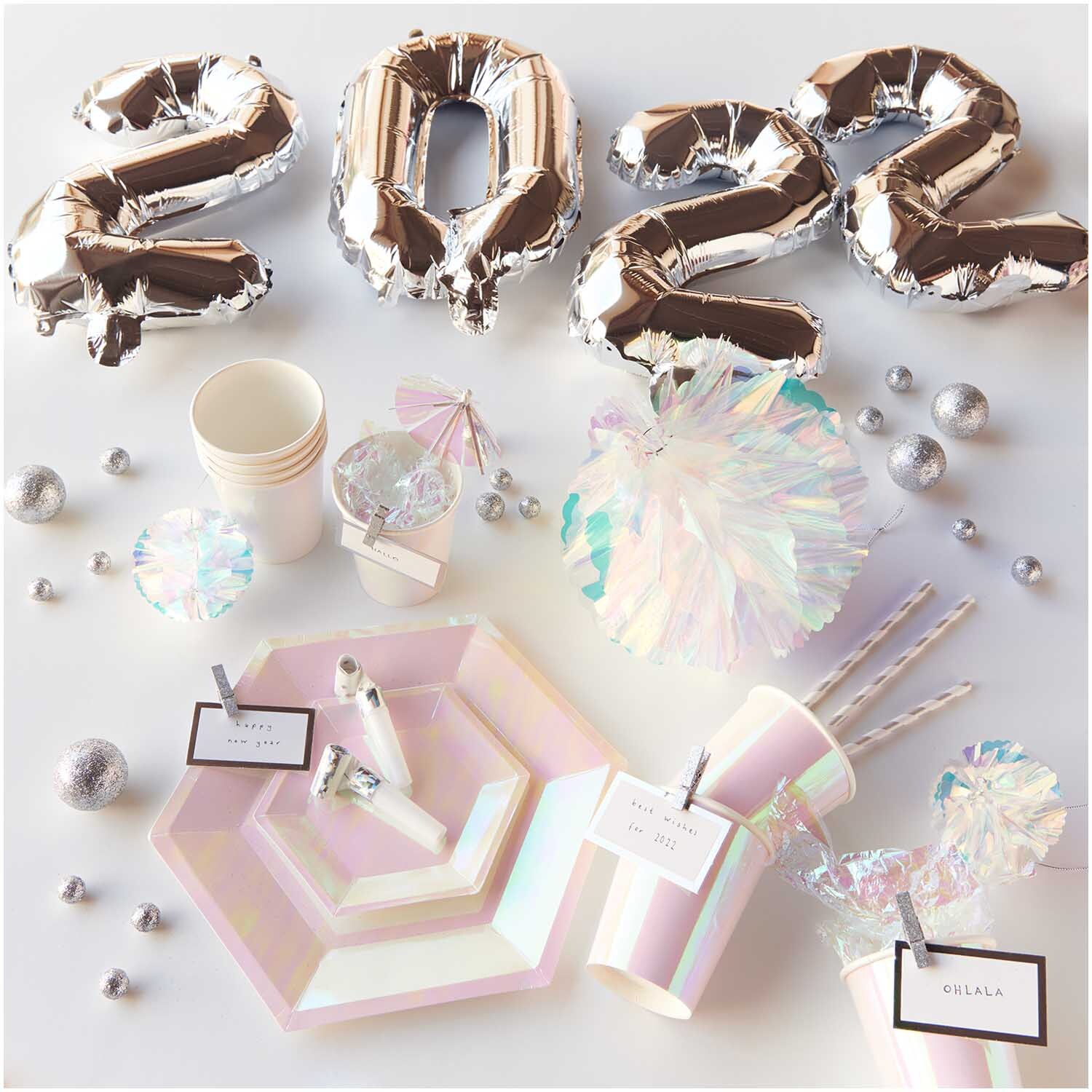 Pappteller holographisch 15,5x13,5cm 10 Stück von Rico Design, umgeben von Partydeko und silbernen Ballons.