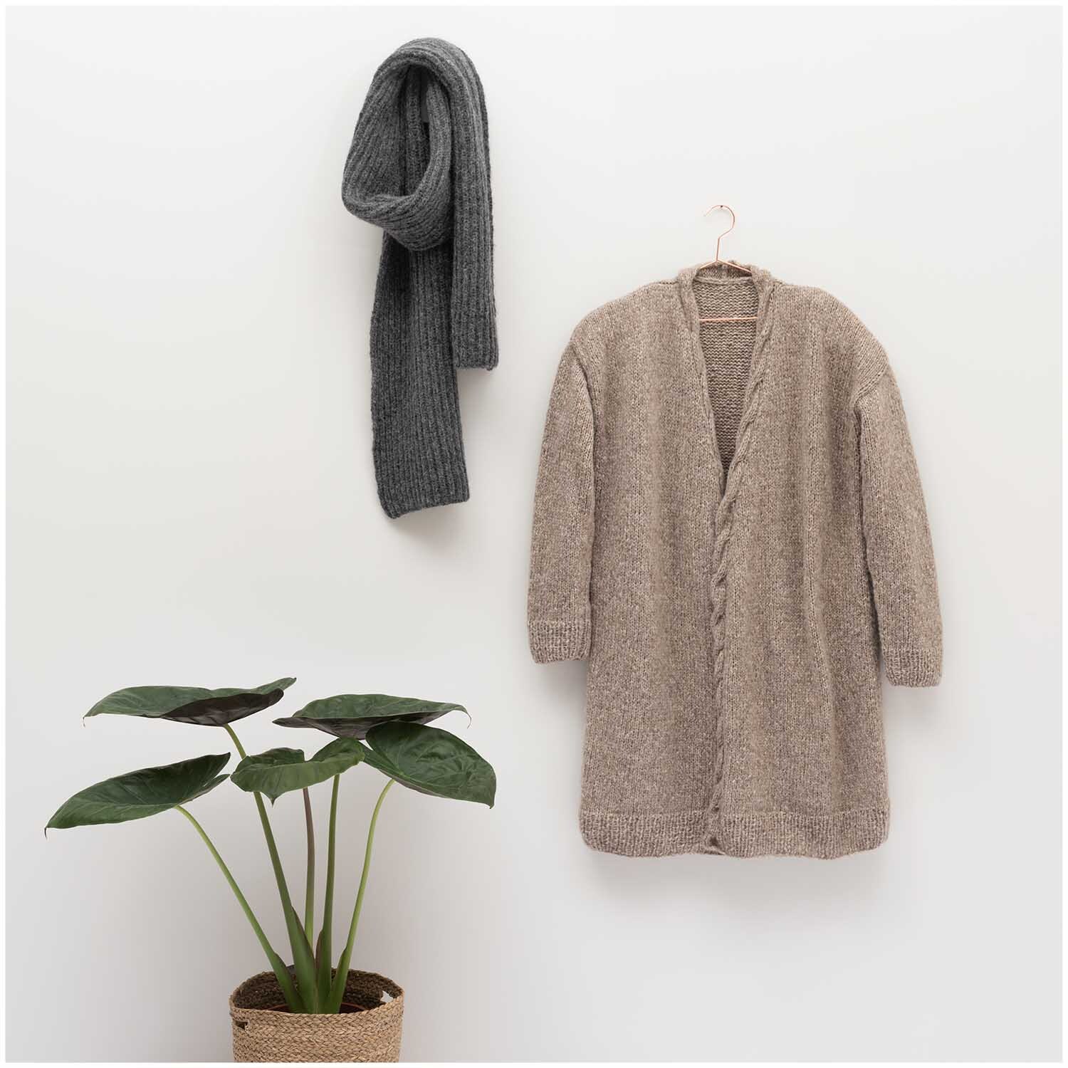 Luxury Baby Alpaca & Merino chunky: Strickjacke und Schal an der Wand, Pflanze im Topf.