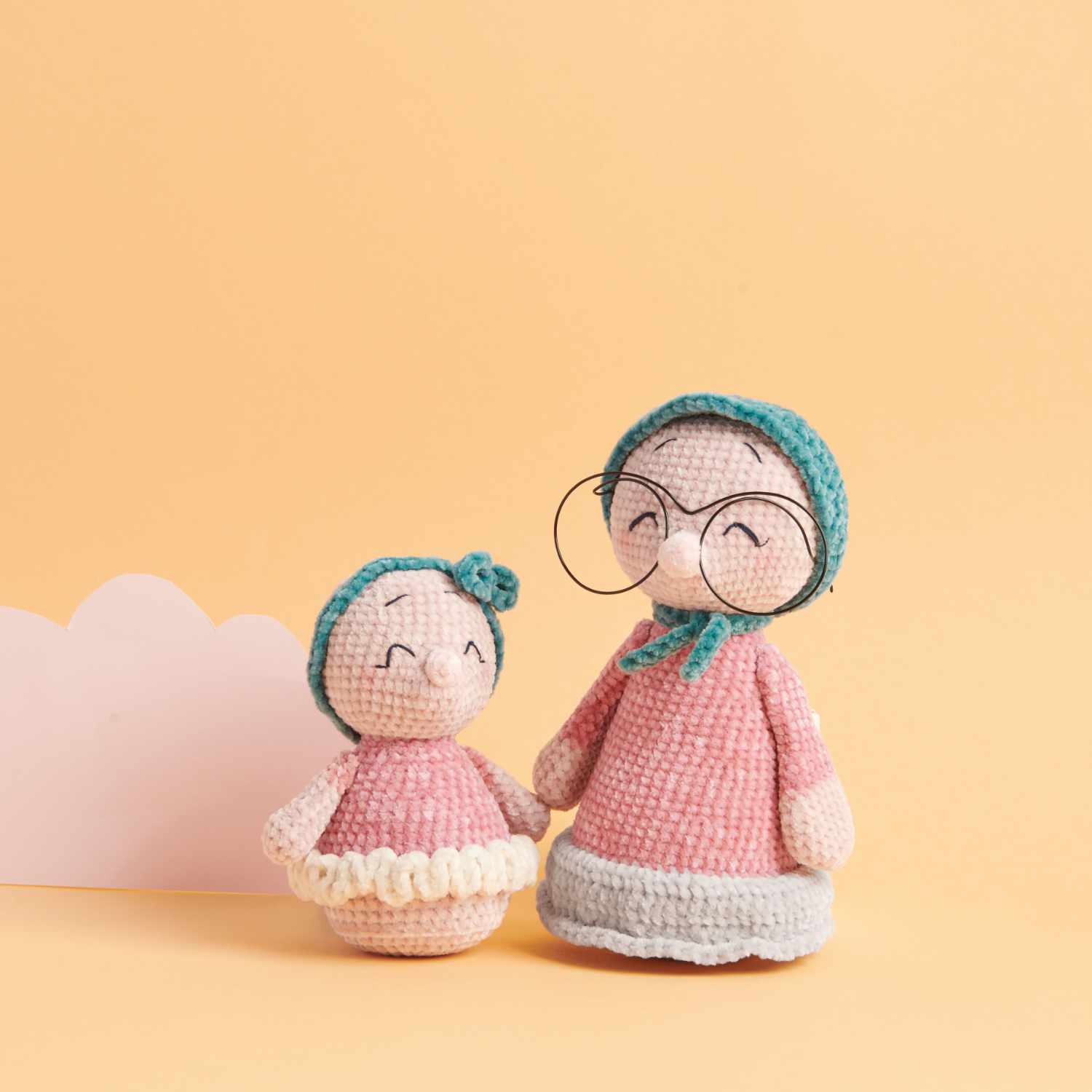 Häkelset Maulwurf-Oma und Marla aus Ricorumi Mini Me: Zwei gehäkelte Figuren in Rosa mit Brille und Mütze vor einem pastellfarbenen Hintergrund.
