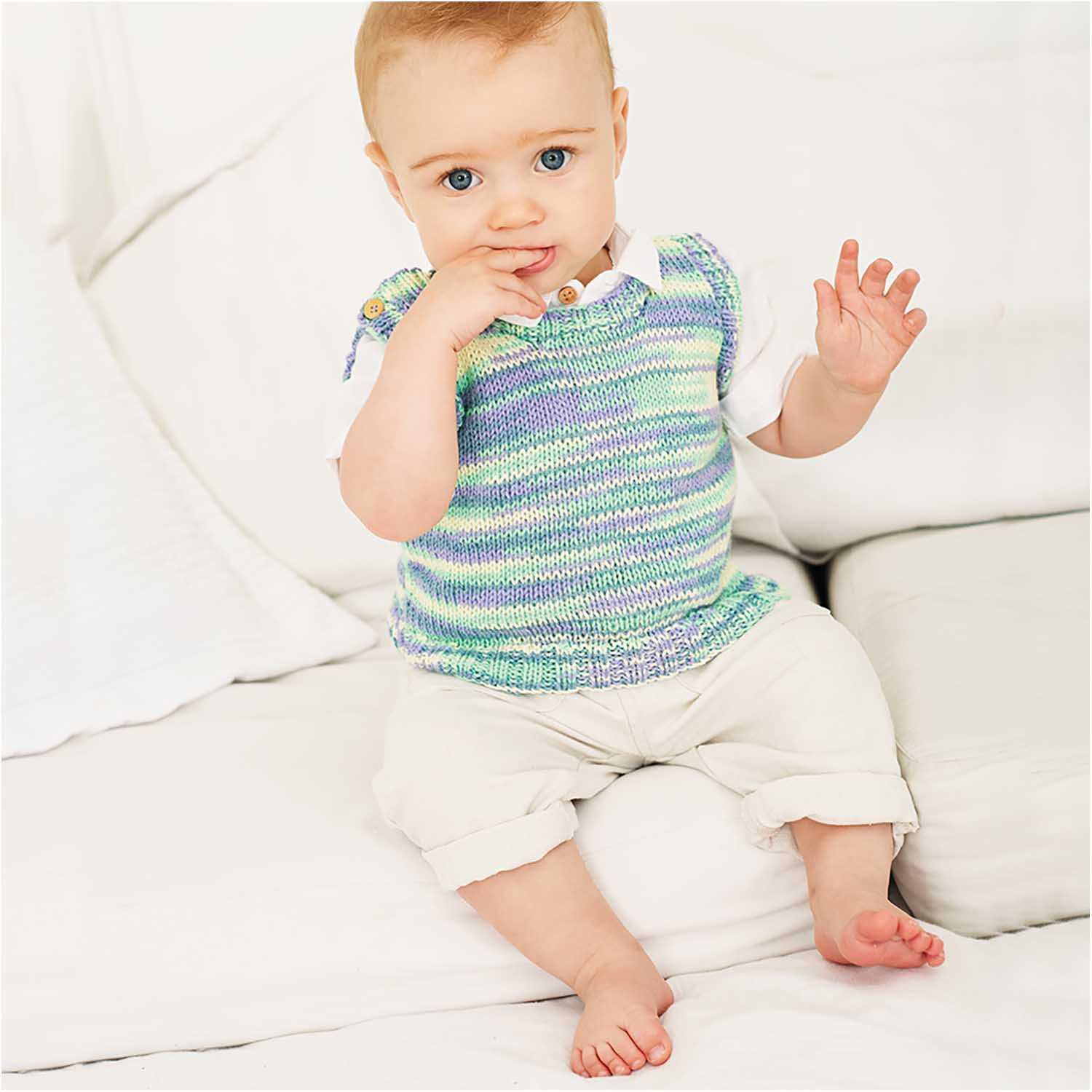 Rico Baby Cotton Soft Print dk: Ein Baby trägt einen gestrickten Pullover in Veilchen-Grün von Rico Design.