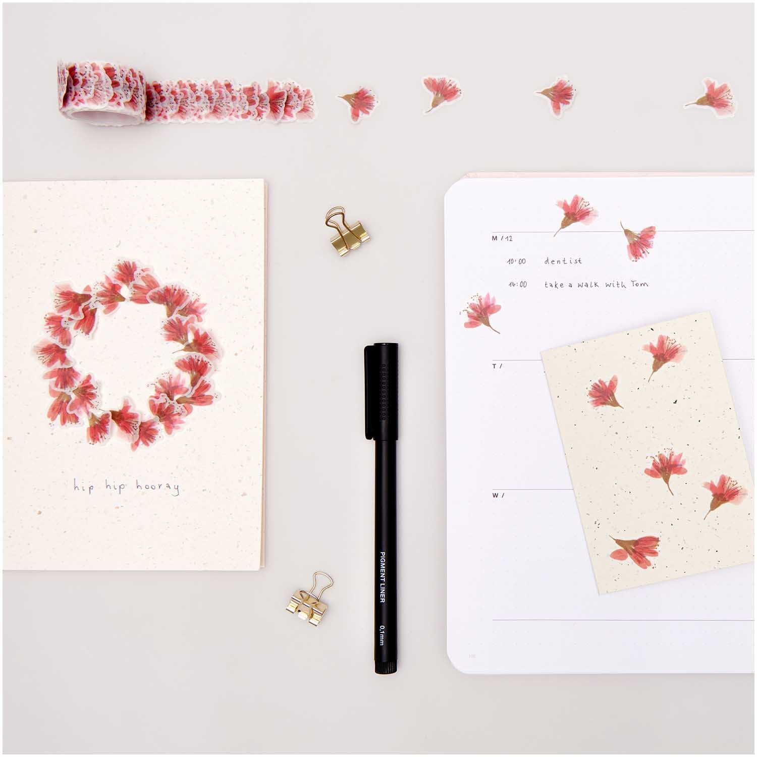 Paper Poetry Pigment Liner schwarz 6 Stifte, umgeben von Notizbüchern und dekorativen Blumenstickern.
