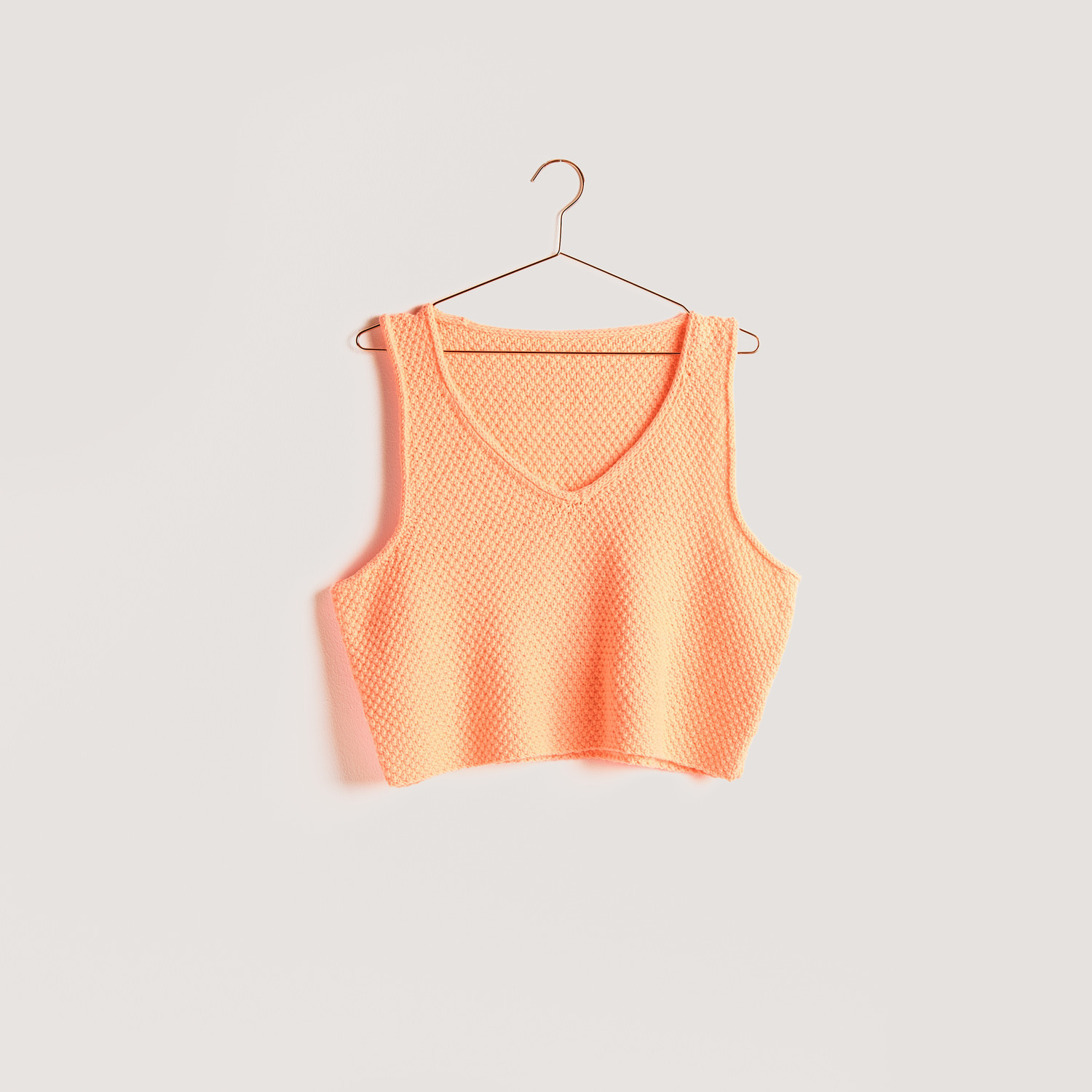 Strickset Top Modell 09b aus Vegan Cashmere in leuchtendem Orange von Rico Design auf einem Kleiderbügel.