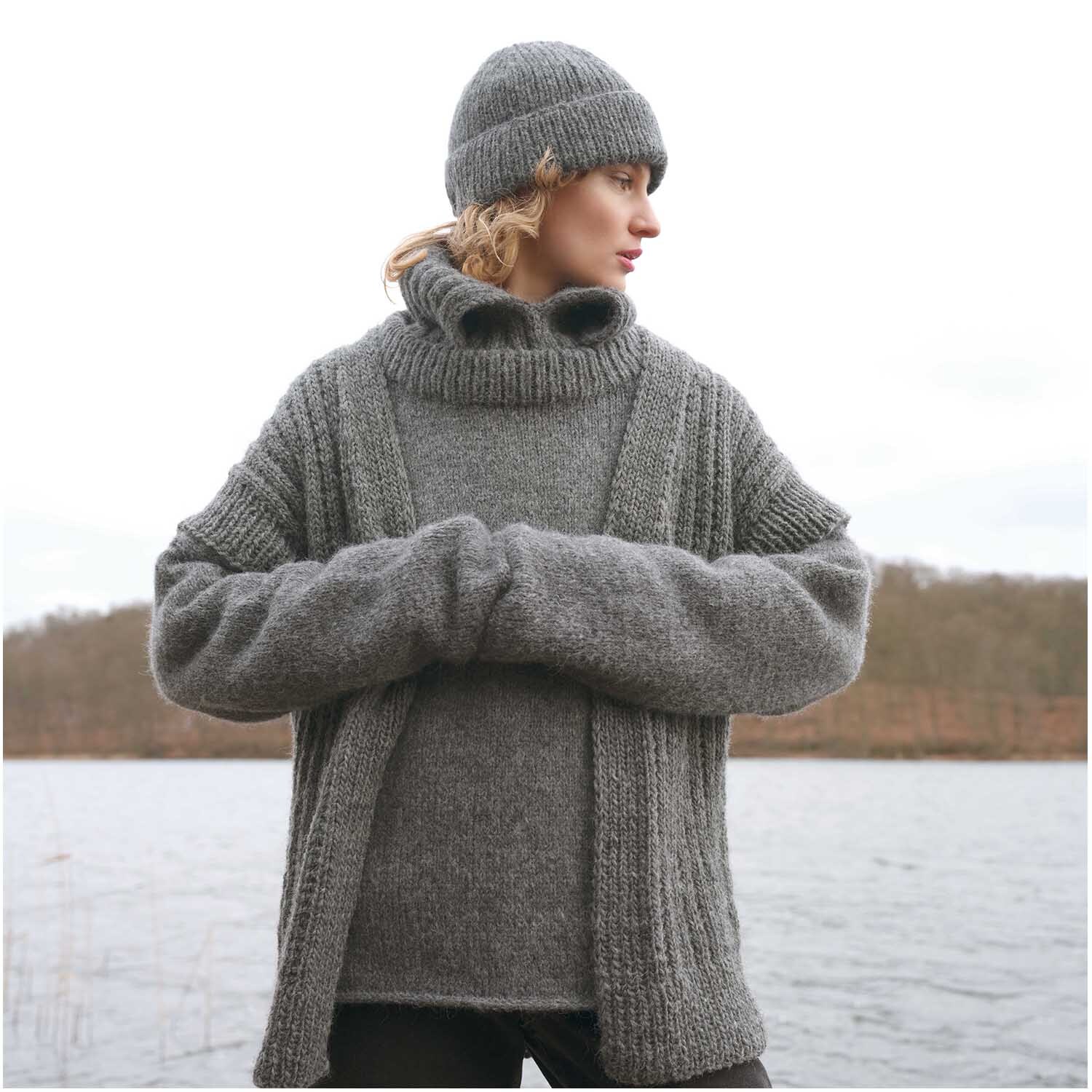 Strickset Kragen Modell 18: Frau in anthrazitfarbenem Strickpullover und Mütze am Seeufer.