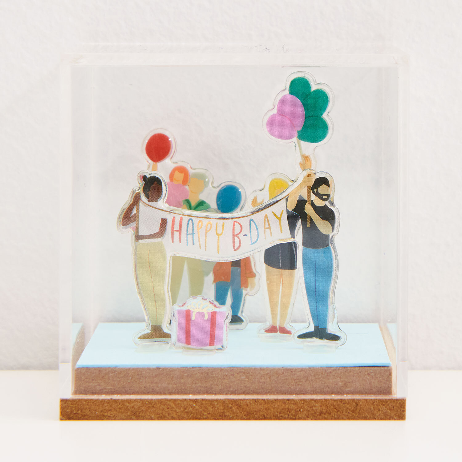 Bastelanleitung Figurico Geburtstag: Bunte Figuren halten ein "Happy B-Day"-Banner, umgeben von Luftballons und Geschenk.