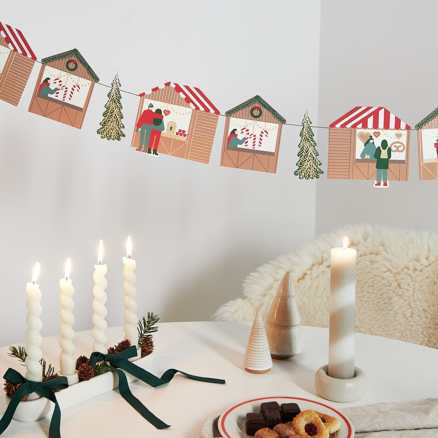 Paper Poetry Genähte Girlande Weihnachtsmarkt dekoriert einen Tisch mit Kerzen und Gebäck.