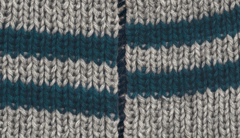 Strickanleitung Herrenmütze mit Streifen zeigt Nahaufnahme von gestricktem Stoff in Grau und Blau. Ideal für stilvolle Winteraccessoires.