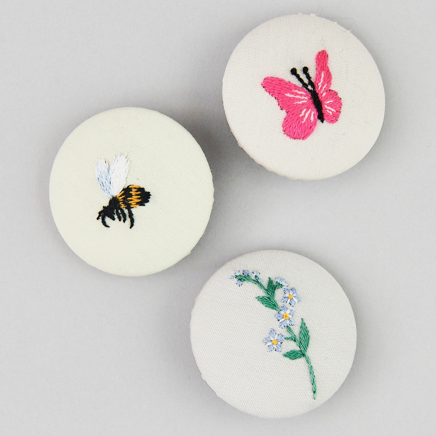 Stick and Stitch Blümchen: Drei bestickte Knöpfe mit Biene, Schmetterling und Blume von Rico Design.