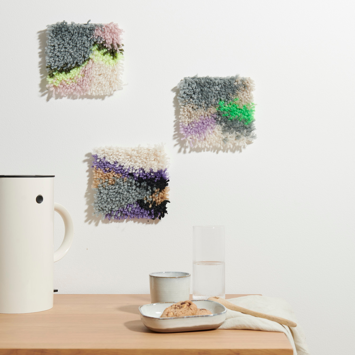 Rico Hooki Hooki Knüpfset Mamorbilder: Drei bunte, texturierte Wandbilder, 14x14cm, von Rico Design, dekorieren eine minimalistische Küche.