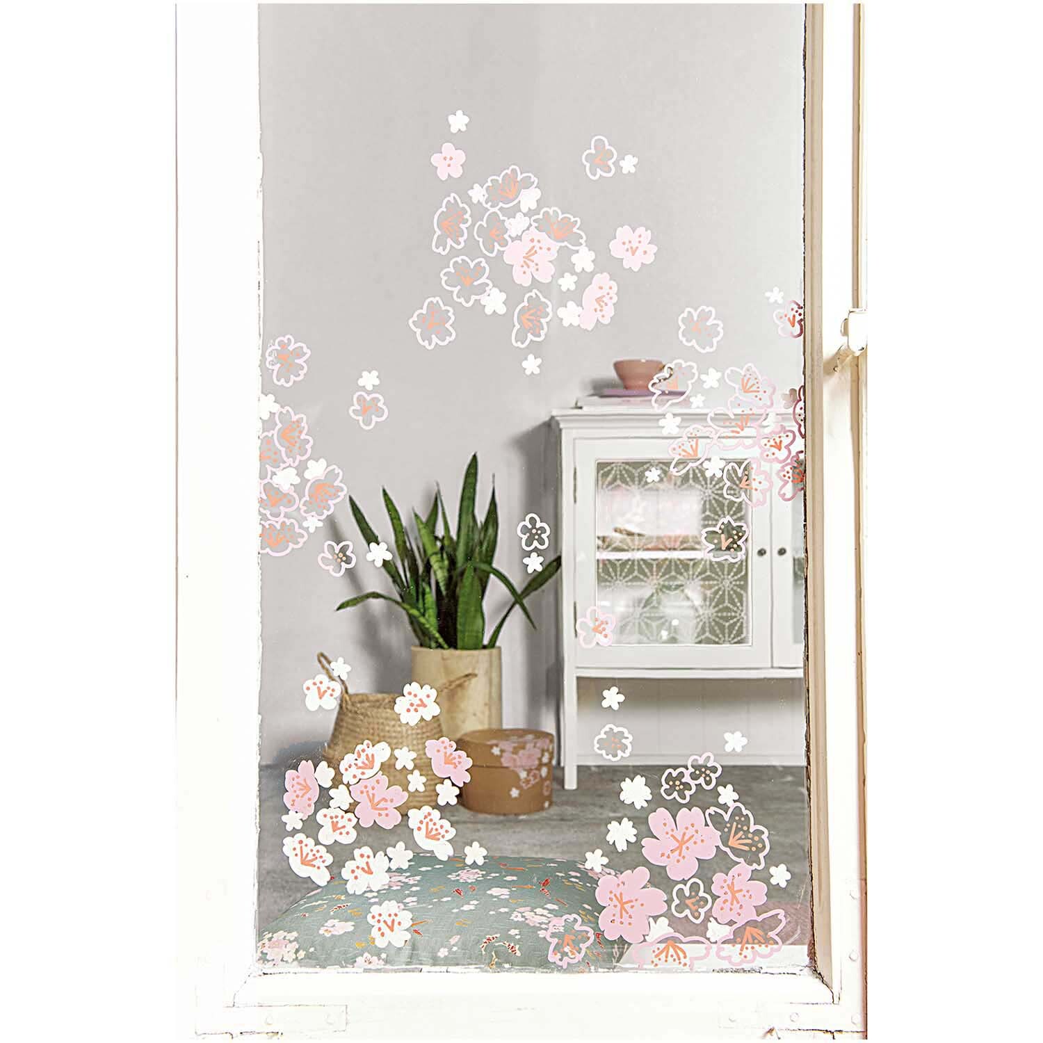 Vorlagenmappe Jardin Japonais: Fenster mit rosa Kirschblüten, dekoriert mit Kreidestiften, im Hintergrund ein weißes Regal und grüne Pflanze.