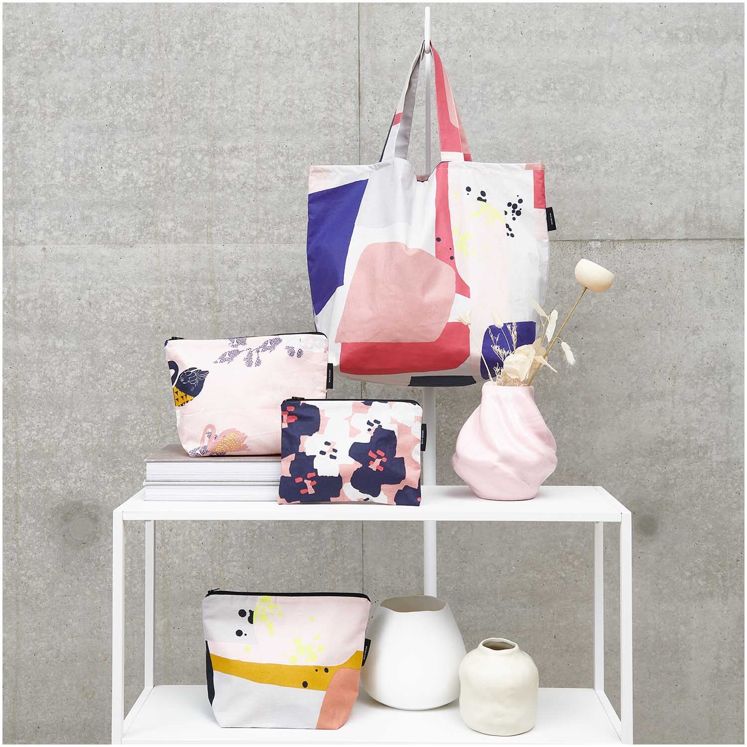 Kosmetiktasche Okina Hana mit grafischem Print, präsentiert auf einem Regal mit weiteren Taschen und Vasen.