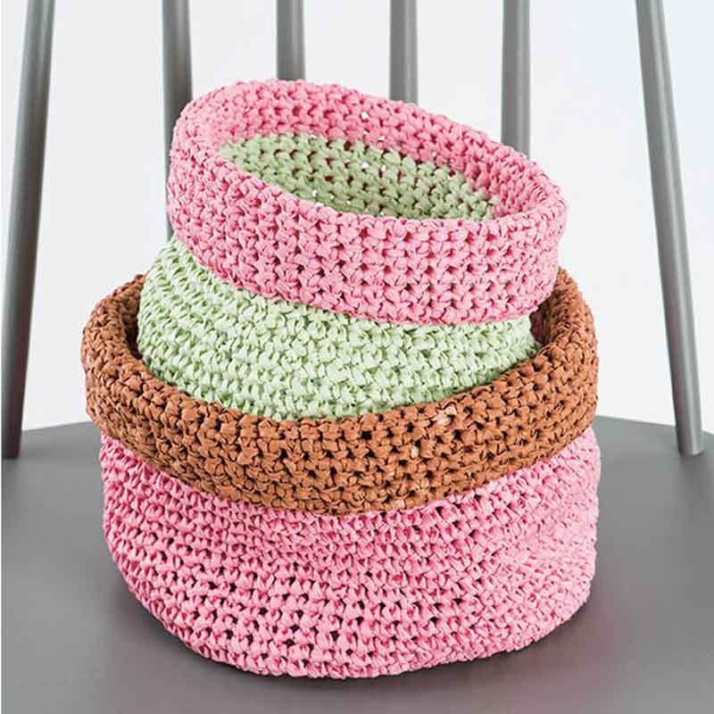 Creative Paper: Drei gehäkelte Körbe in Rosa, Grün und Braun von Rico Design auf einem Stuhl.