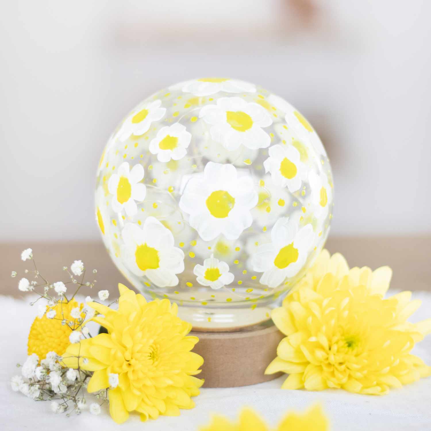 Inspiration Glasdekohaube mit Blumenmuster aus Acrylfarbe, umgeben von gelben Blüten auf weißem Hintergrund.
