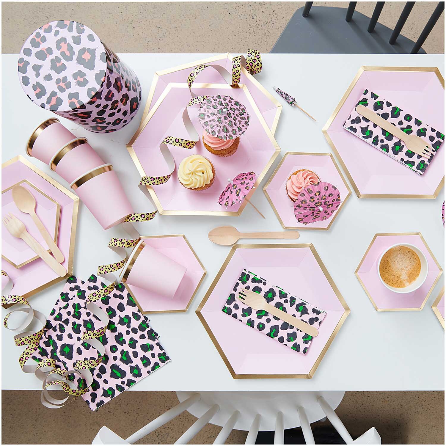 Pappteller Sechseck rosa-gold von Rico Design auf einem Tisch mit Partyzubehör und Snacks.