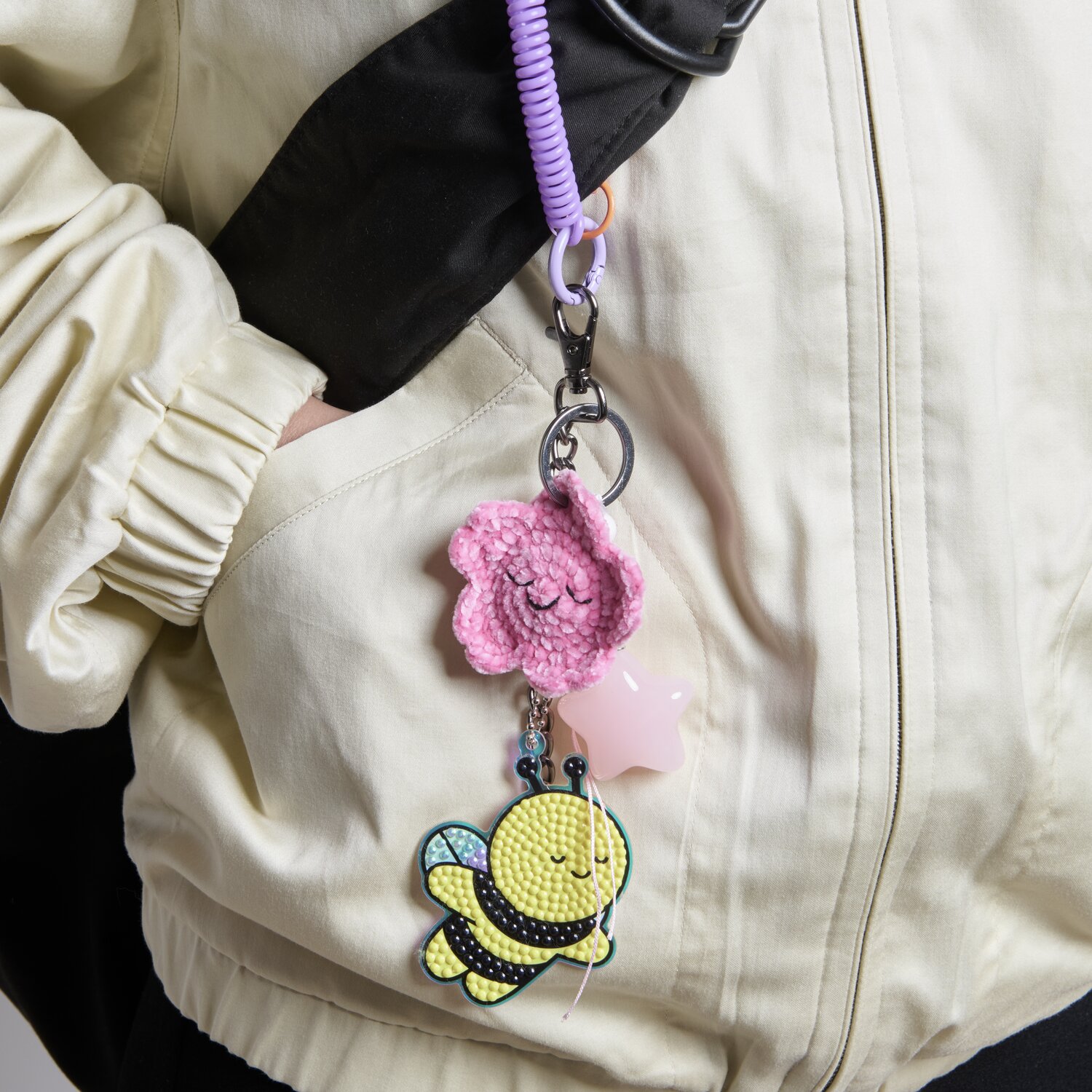 Karabiner mit Kette und Schlüsselring 13cm, verziert mit rosa Blume und gelber Biene, an einer hellen Jacke befestigt.