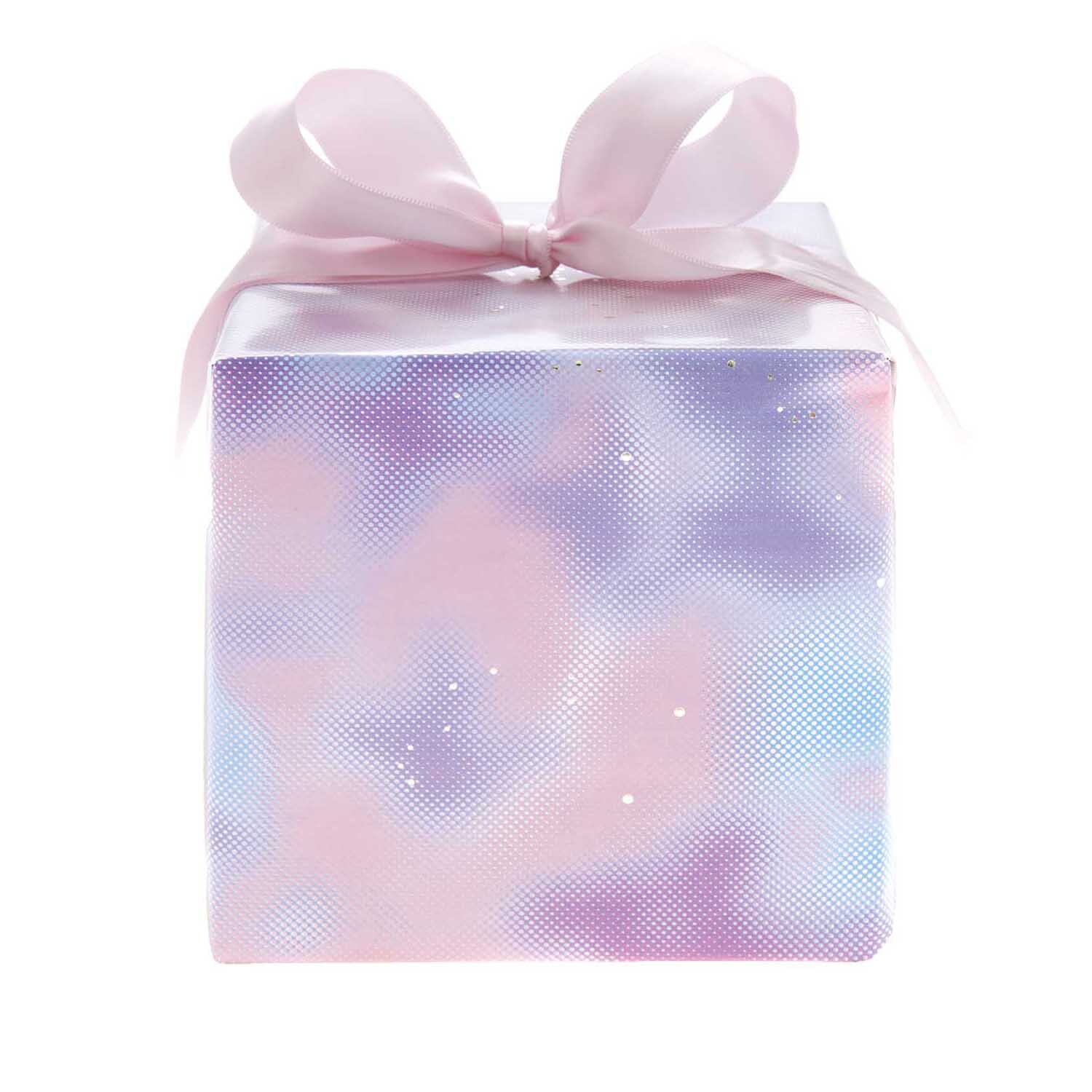 Paper Poetry Geschenkpapier zeigt ein verschwommenes blaues Muster, verpackt mit rosa Schleife. Ideal für stilvolle Geschenke. Marke: Rico Design.