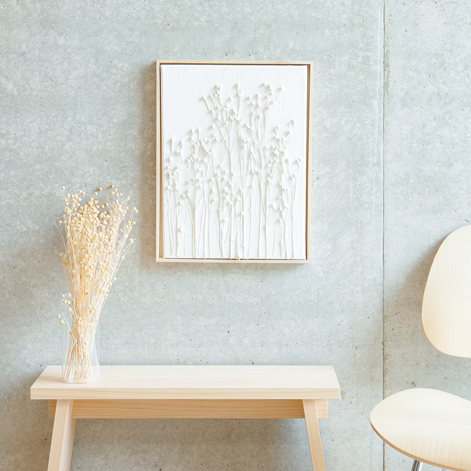 Anleitung Leinwand mit Strukturpaste zeigt Trockenblumen auf hellem Hintergrund, neben Holzbank.