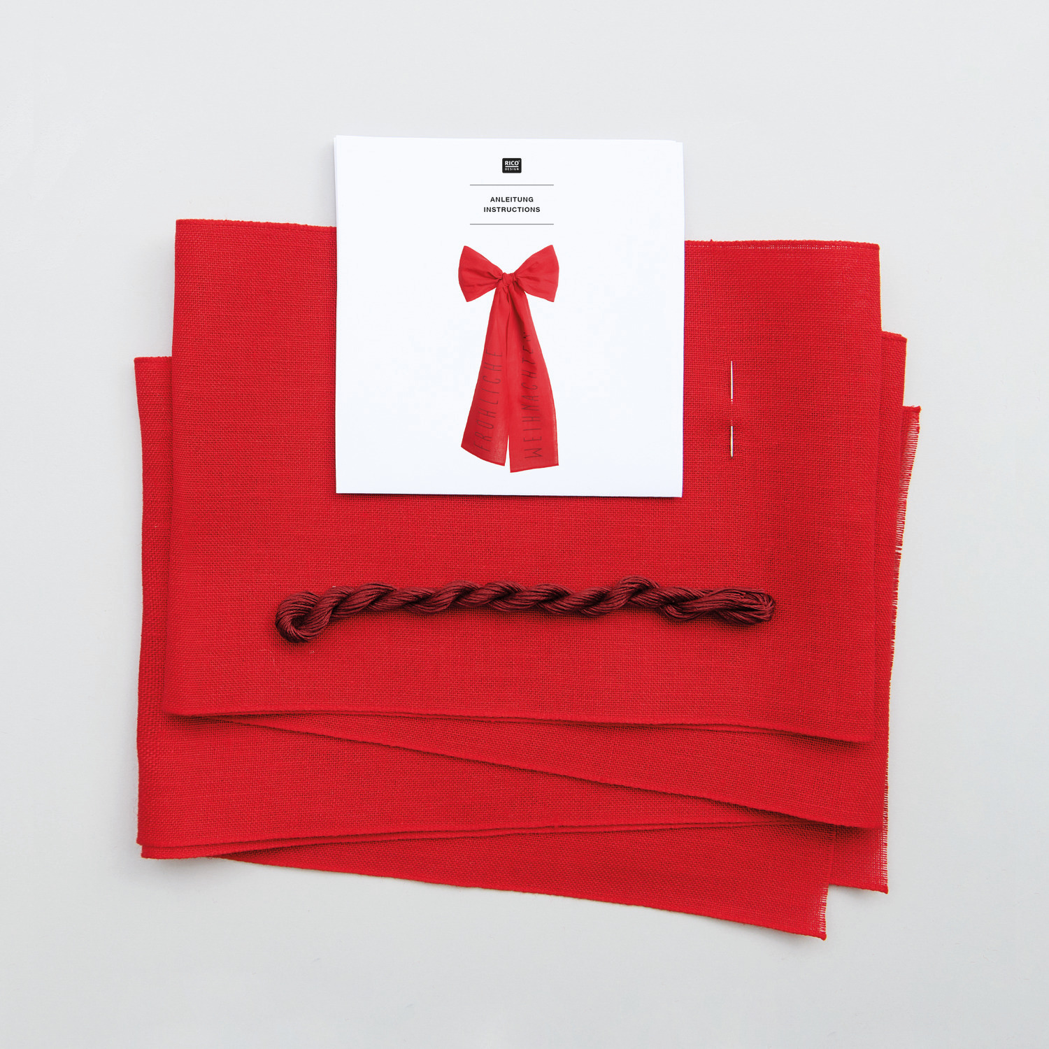 Stickpackung Schleife Fröhliche Weihnachten von Rico Design: Rotes Stickset mit Schleifenmotiv und Anleitung auf weißem Hintergrund.