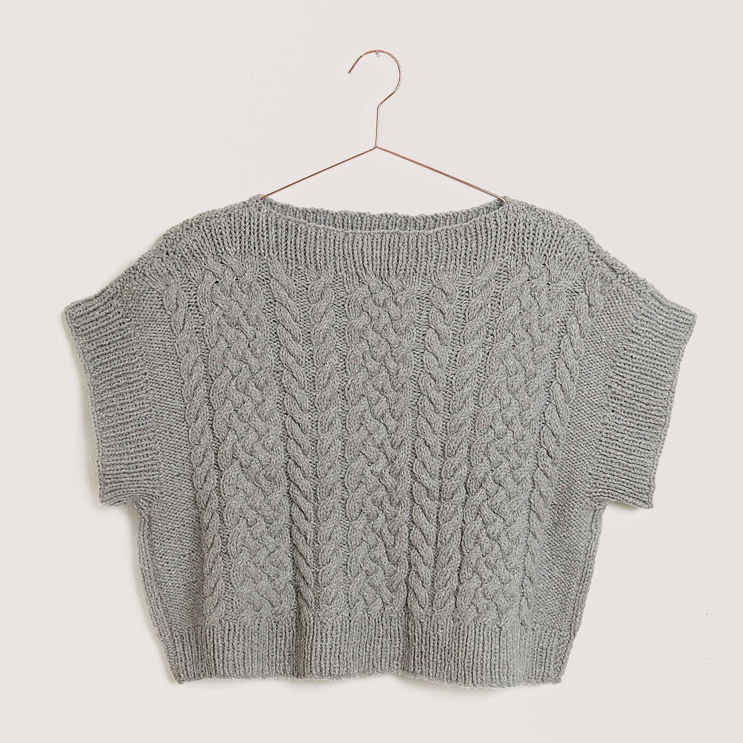 Luxury Natural Silk Blend: Grauer Strickpullover mit Zopfmuster, hängend auf einem Kleiderbügel. Ideal für stilvolle, gemütliche Outfits.