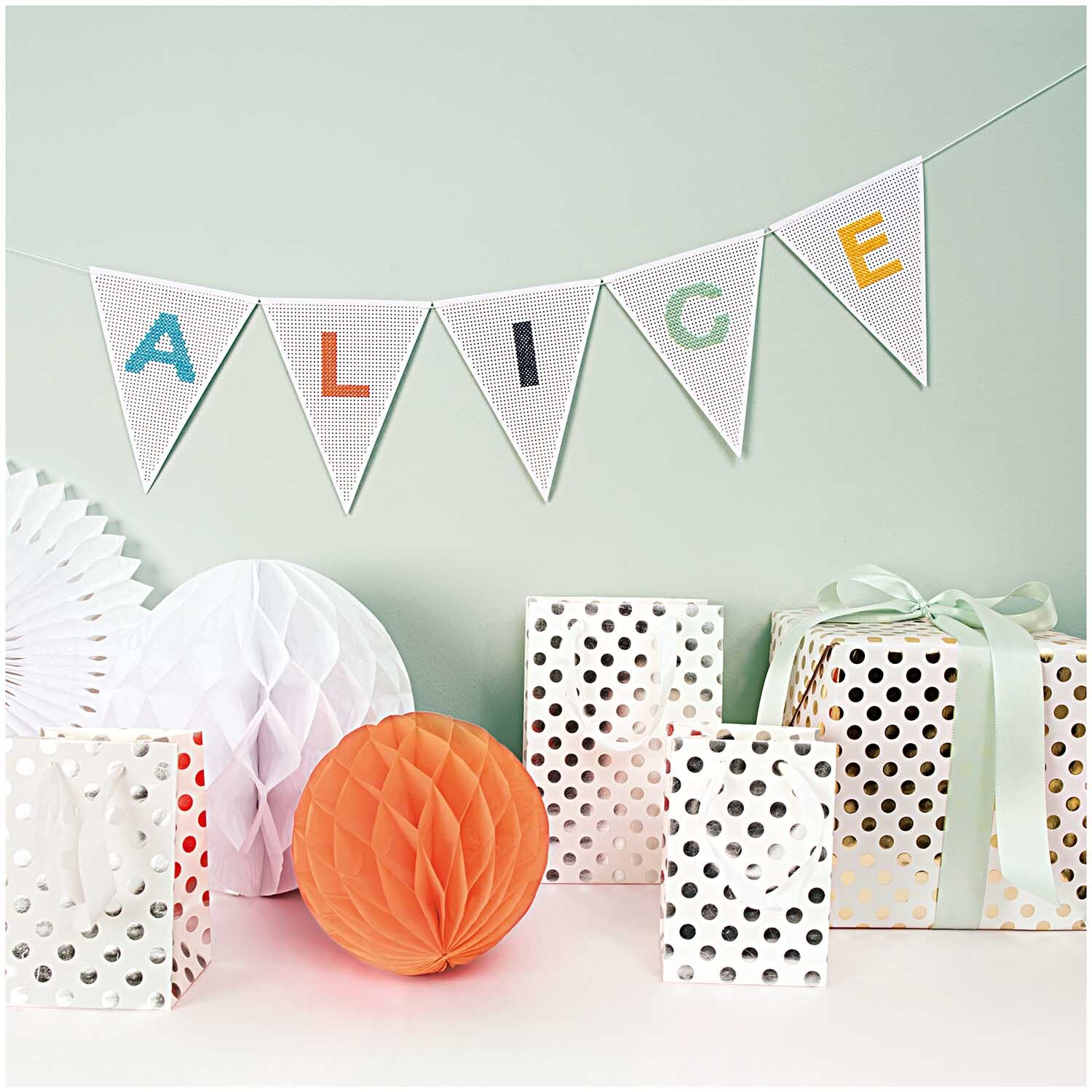 Wabenpapier Bälle mehrfarbig 3 Stück von Rico Design vor einer Dekoration mit Geschenken und Girlande.