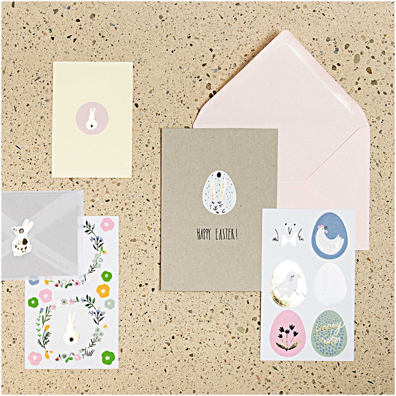 Paper Poetry Sticker Bunny Hop Hasen 44 Stück: Verschiedene Osterkarten und Umschläge mit Hasen- und Blumenmotiven auf einem Tisch arrangiert.