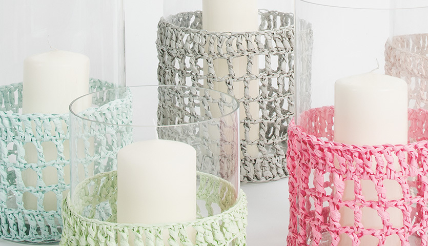 Häkelanleitung Windlichter Doppelstäbchen aus Creative Paper: Bunte Windlichter mit gehäkelten Hüllen in Pastelltönen umgeben weiße Kerzen in Glasgefäßen.