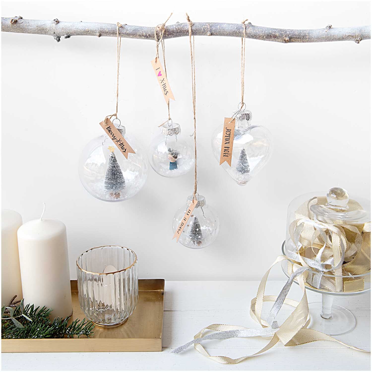 Weihnachtskugel Herz aus Kunststoff von Rico Design, transparent, hängt an einem Ast, umgeben von weiteren Dekorationen.